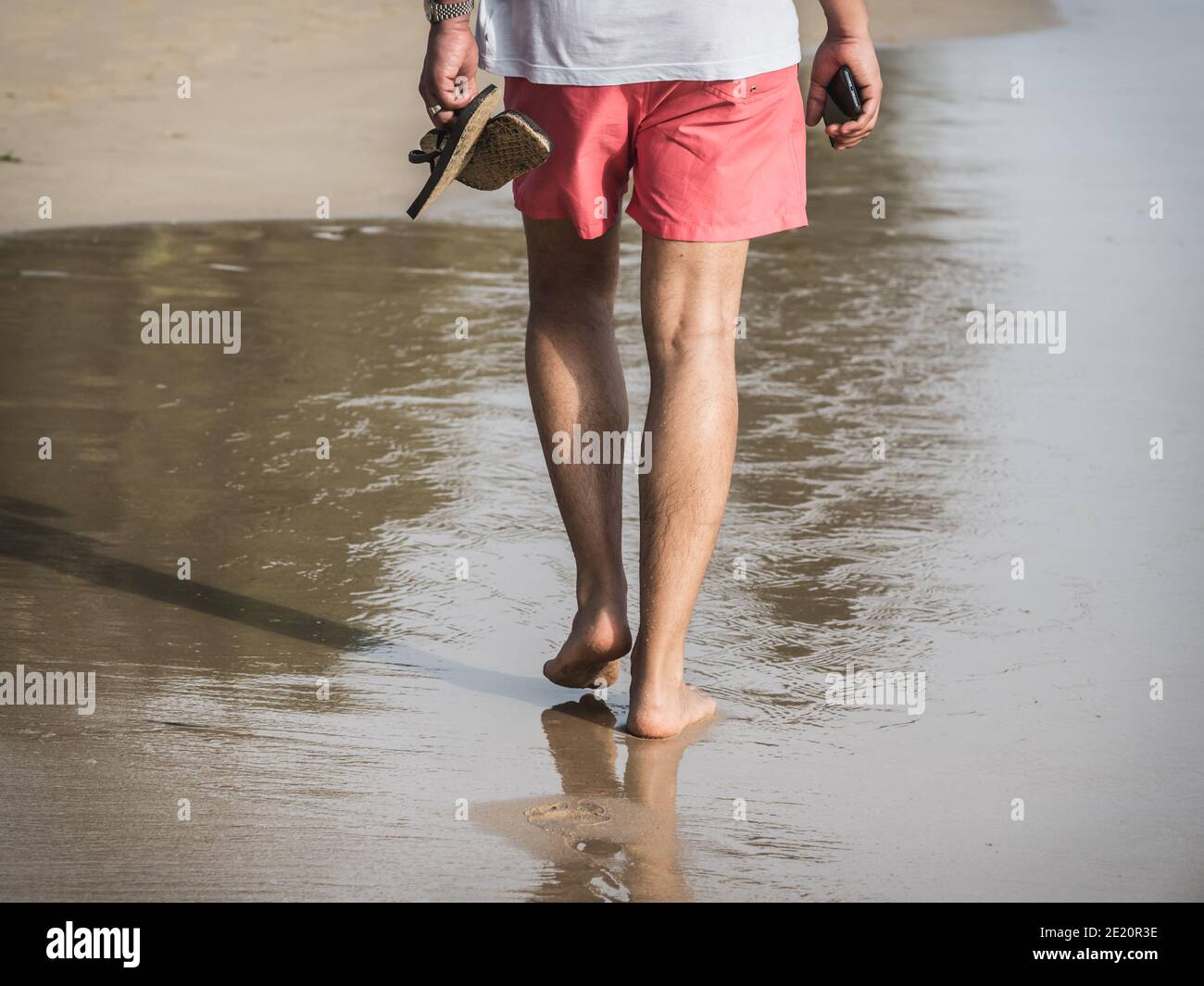 A male holidaymaker wearing Chicago Bulls Basketball Red Just Don Shorts  over white leggings and trainers on Fistral Beach in Newquay in Cornwall in  t Stock Photo - Alamy