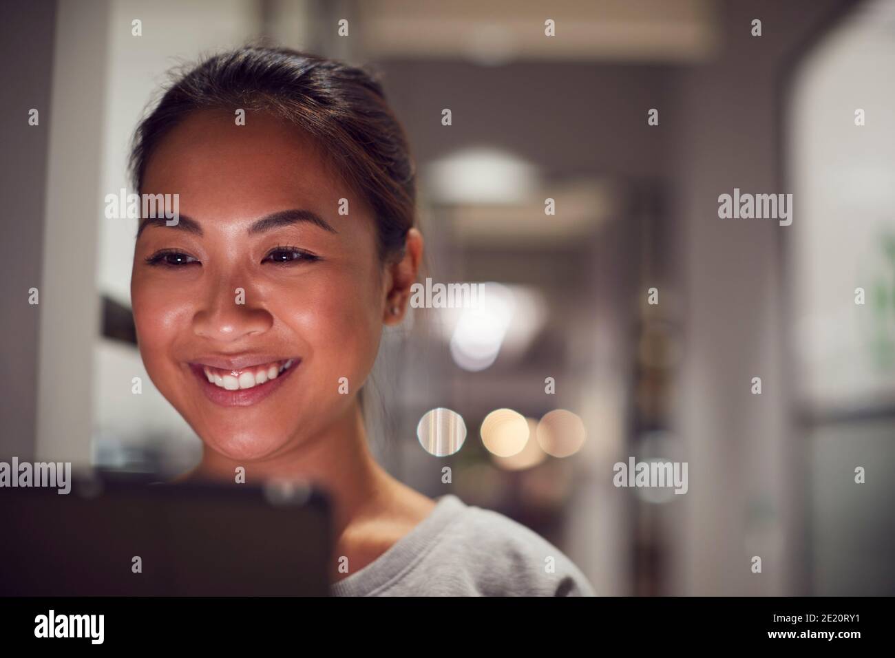 Evening Shot Of Businesswoman Standing In Corridor Of Modern Office Using Digital Tablet Stock Photo