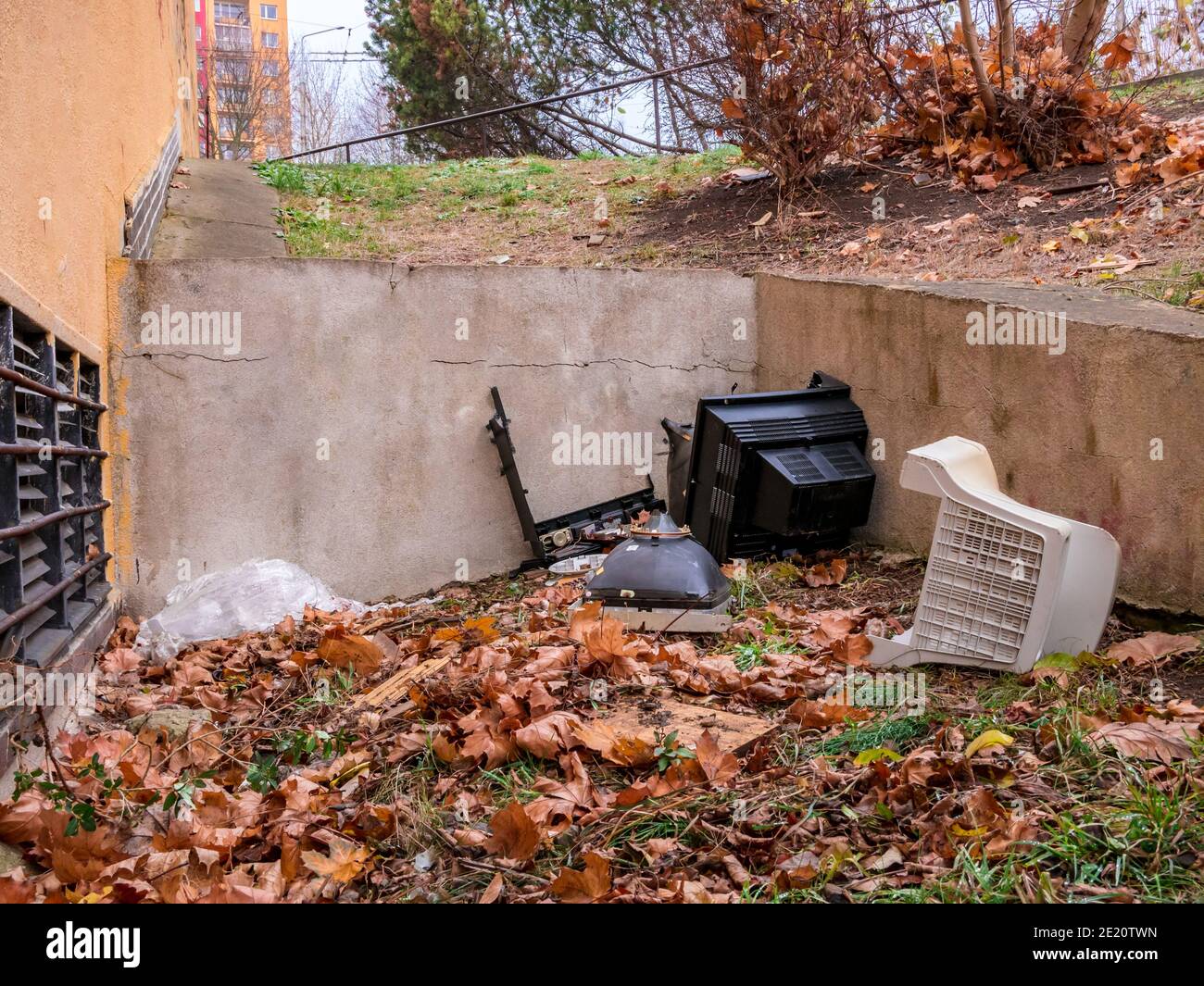 Old CRT computer and TV monitors smashed to pieces in dark corner of populated area. Stock Photo