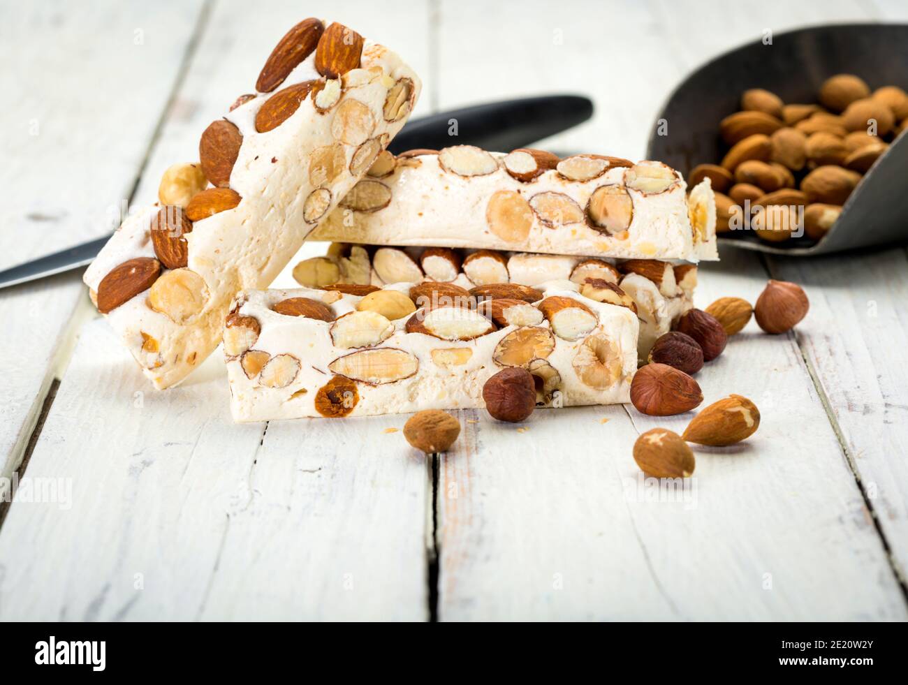 Turron blocks with almonds and hazelnuts on rustic wooden table with knife and shovel Stock Photo