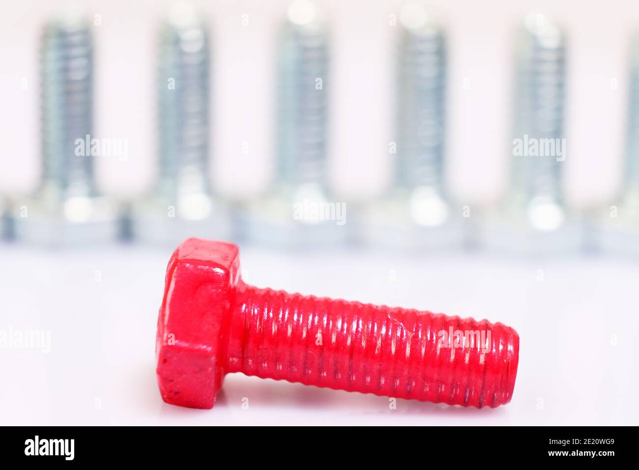 Closeup of fallen, lying pink bolt n a group of galvanized metallic screws. Originality, individuality, dissimilarity concept. Stainless steel bolts i Stock Photo