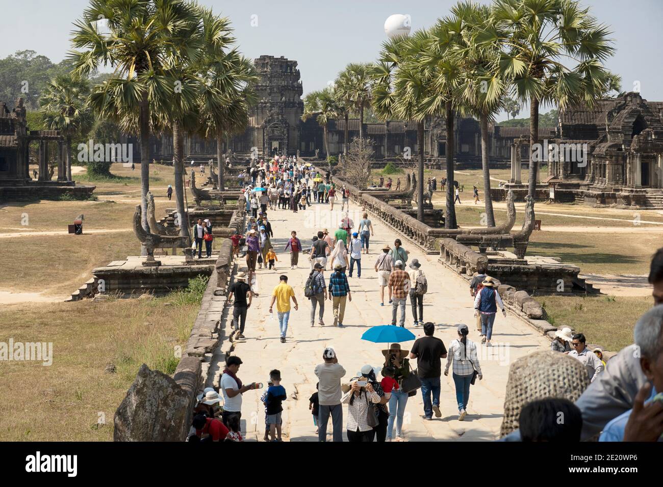 Tourists walking down the road to Angkor Wat Stock Photo