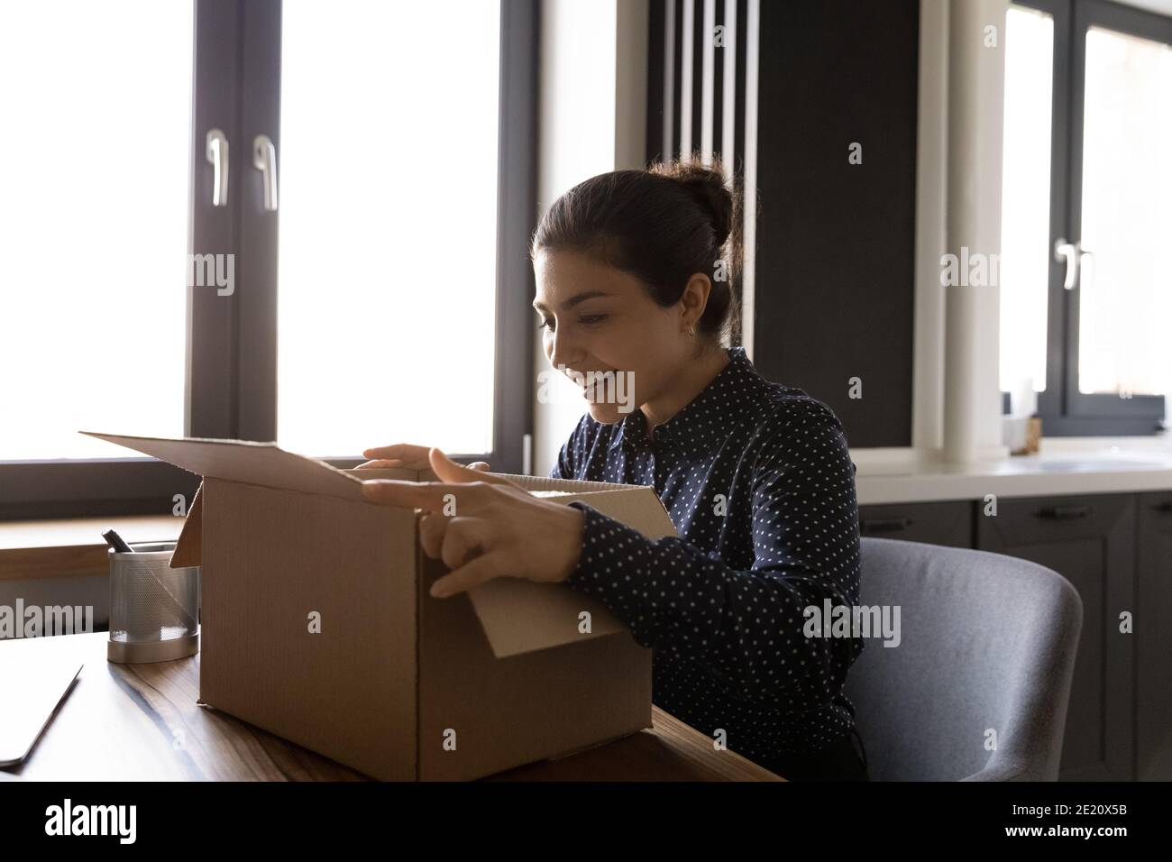 Excited Indian woman unpack parcel shopping online Stock Photo