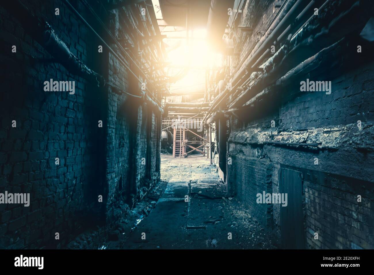 Dark dirty corridor in abandoned industrial factory with light in end, horror concept. Stock Photo