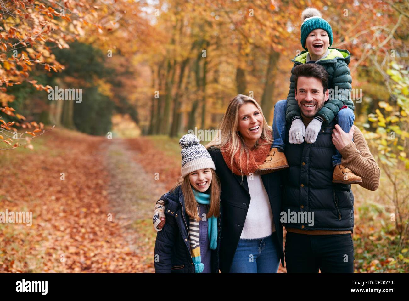 Portrait Of Family Walking Along Autumn Woodland Path With Father ...