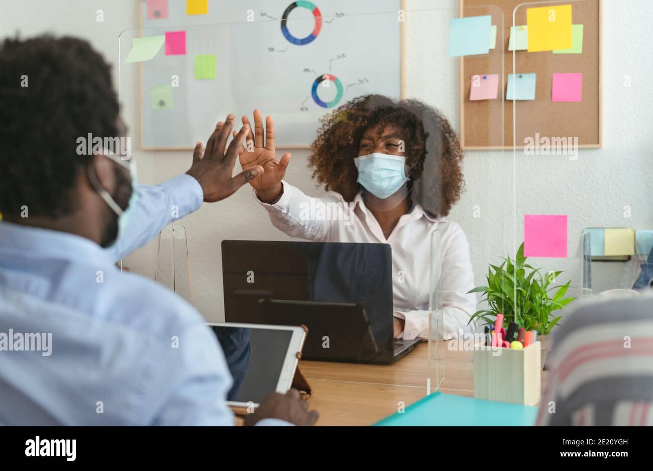 Young African people in co-working creative space wearing surgical mask protection and keeping social distance to avoid corona virus spread Stock Photo