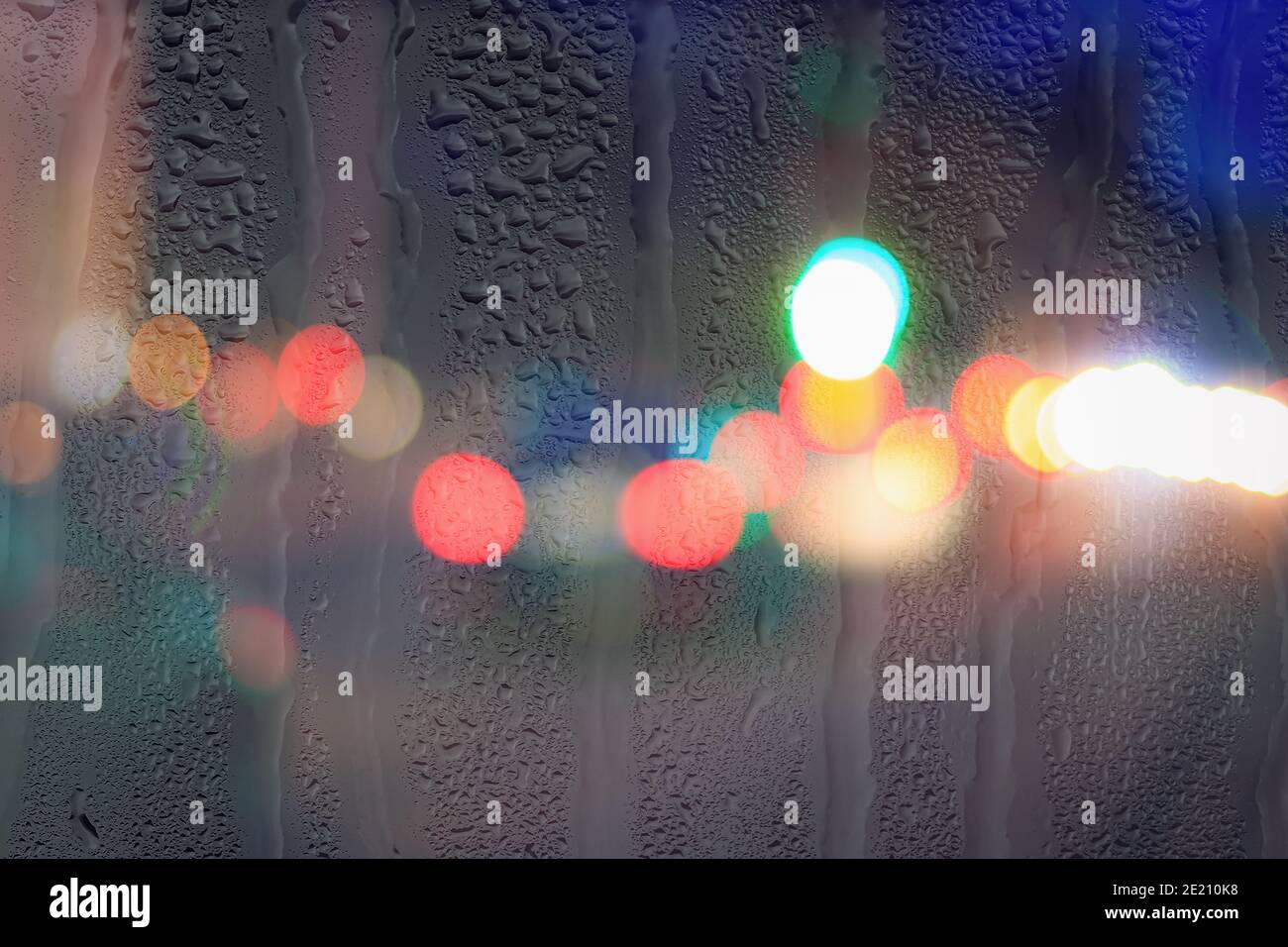 Night city lights and car headlights through rainy glass. Rain and bad