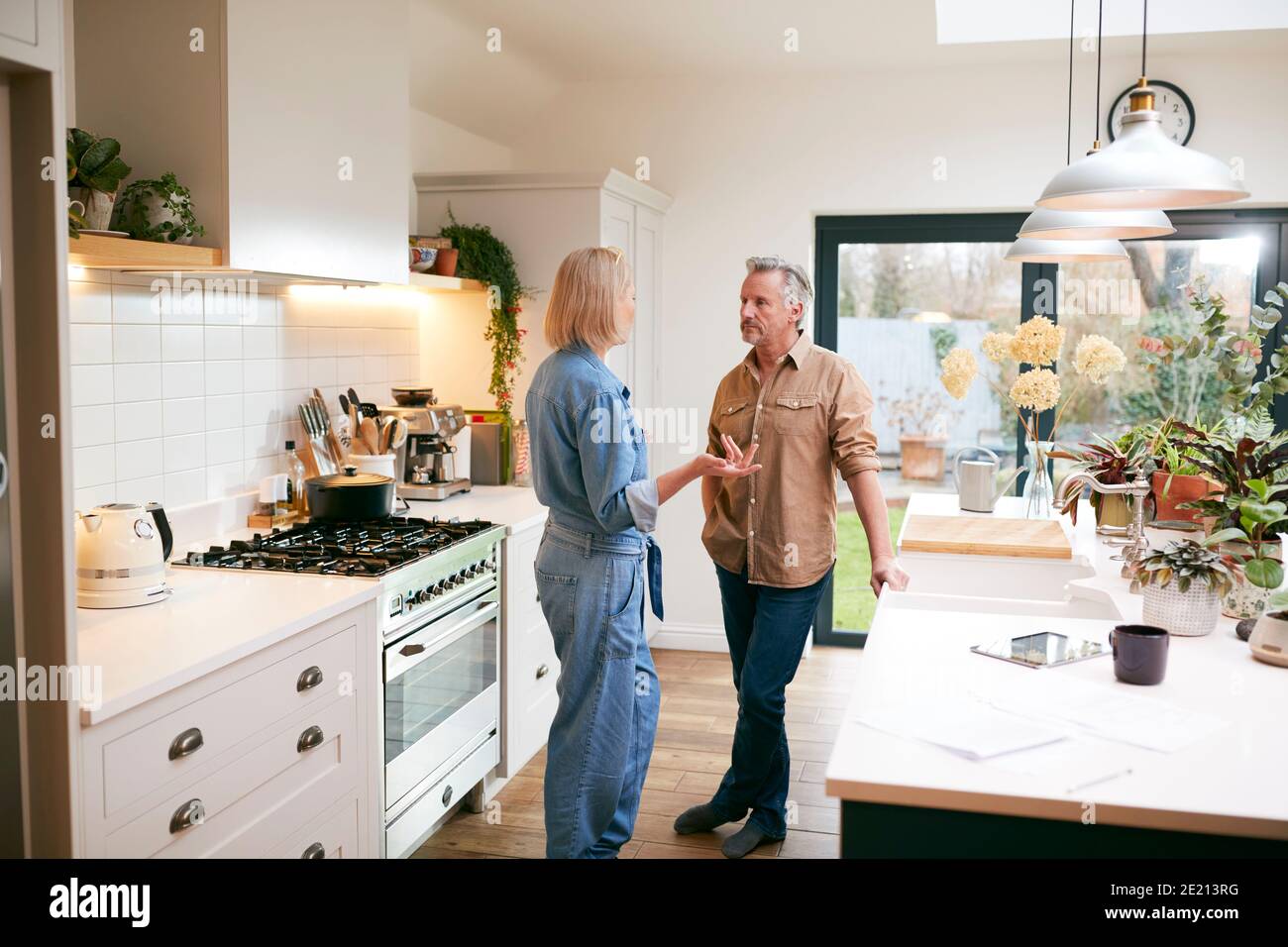 Mature Couple Having Discussion In Kitchen At Home Together Stock Photo