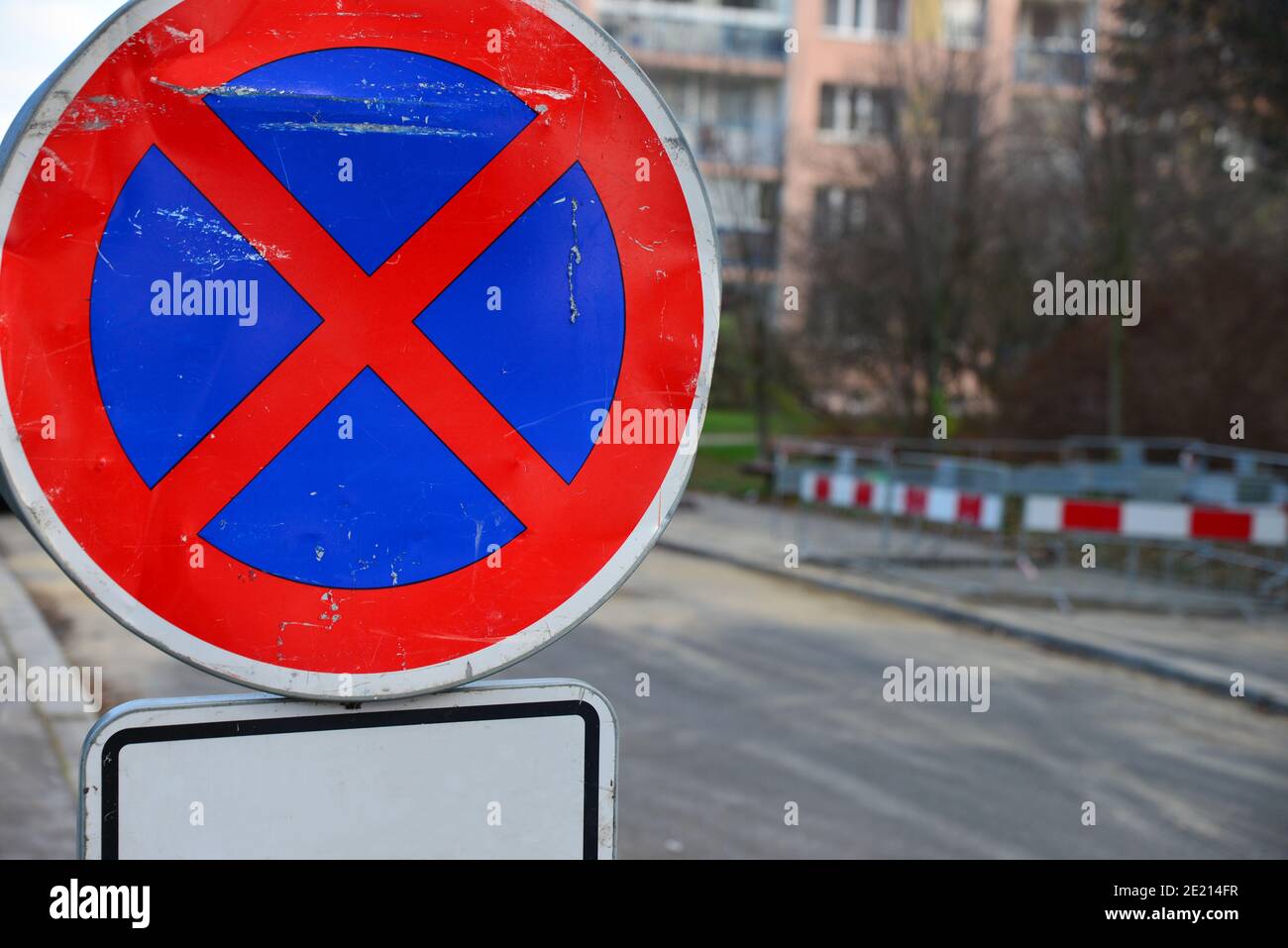 Road sign no stopping with white complementary sign. In the background a road with a demarcated excavation. Site of construction work on the road, mar Stock Photo