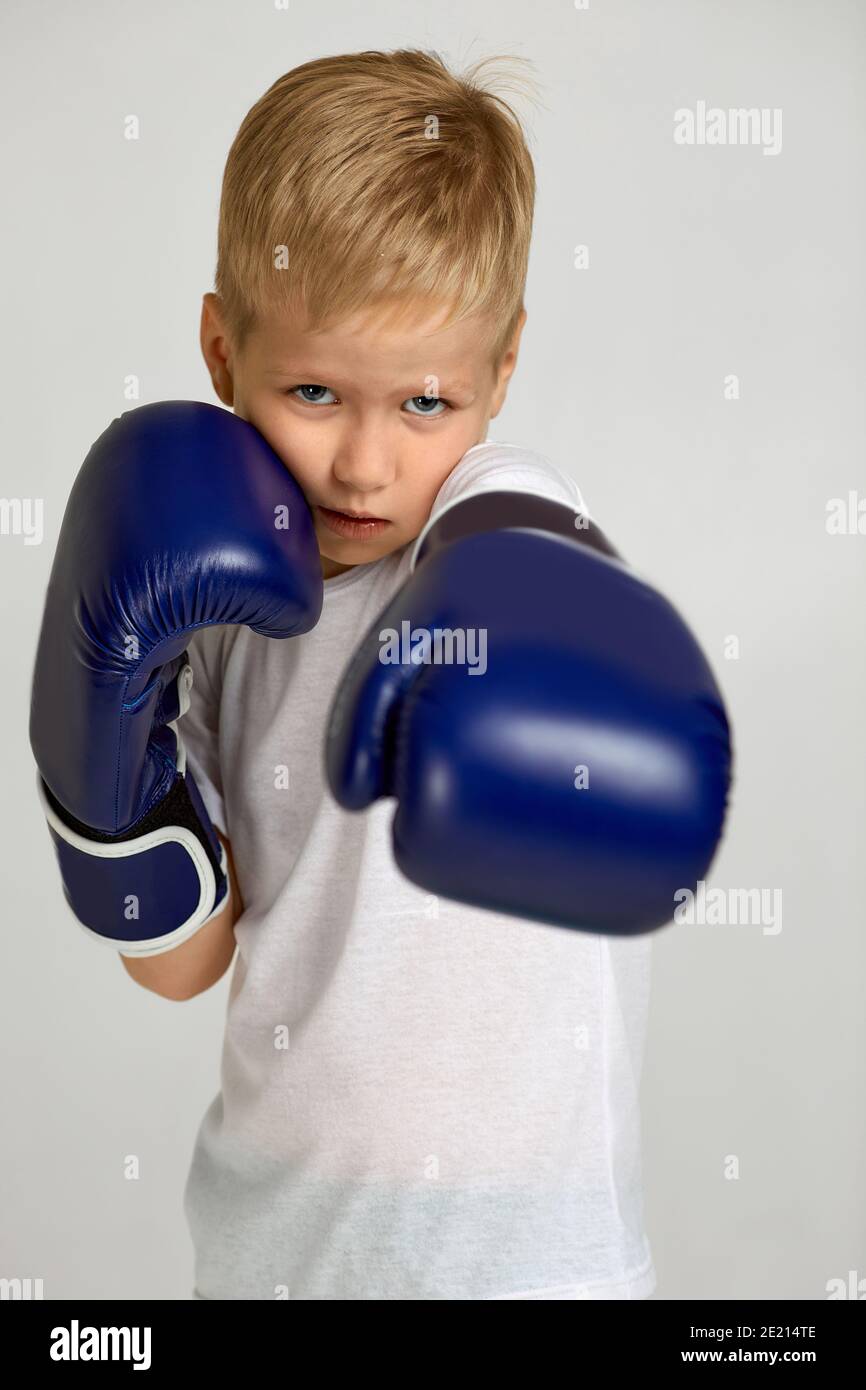 portrait of little boxing fighter boy in blue boxer gloves. child dreams of a boxing