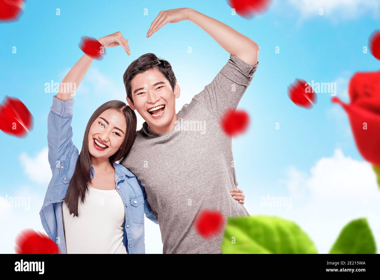 Asian couples making the shape of a heart with hands with a blue sky ...