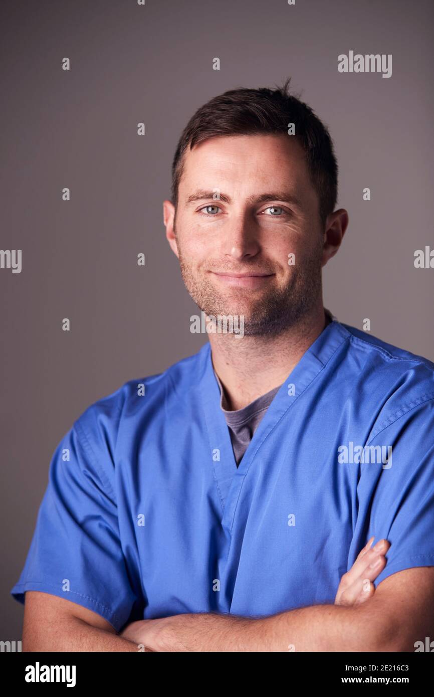 Studio Portrait Of Male Nurse Wearing Scrubs Standing Against Grey