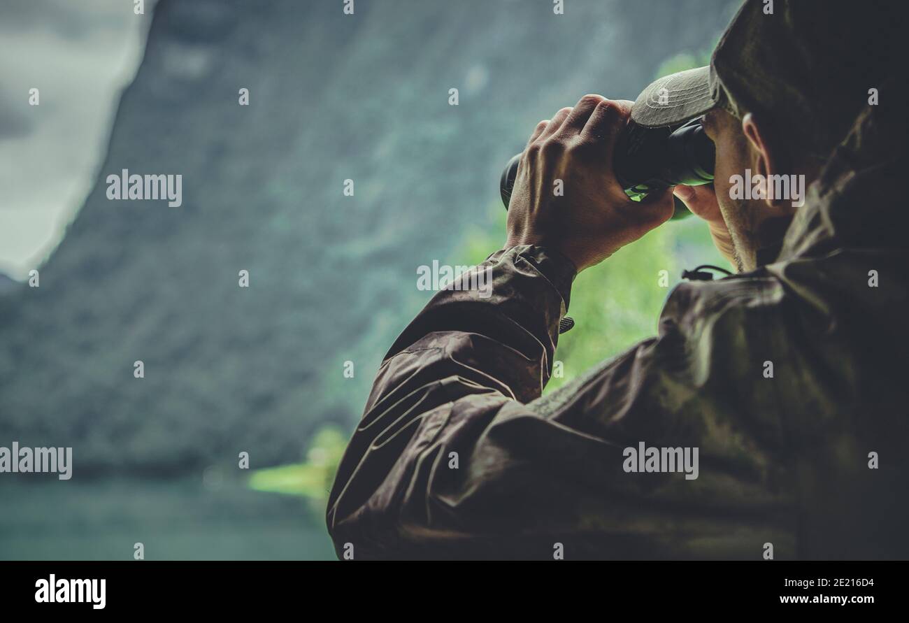 Professional Hunter Wearing Camouflage Uniform Spotting Game with Binoculars. Hunting Season Theme. Stock Photo