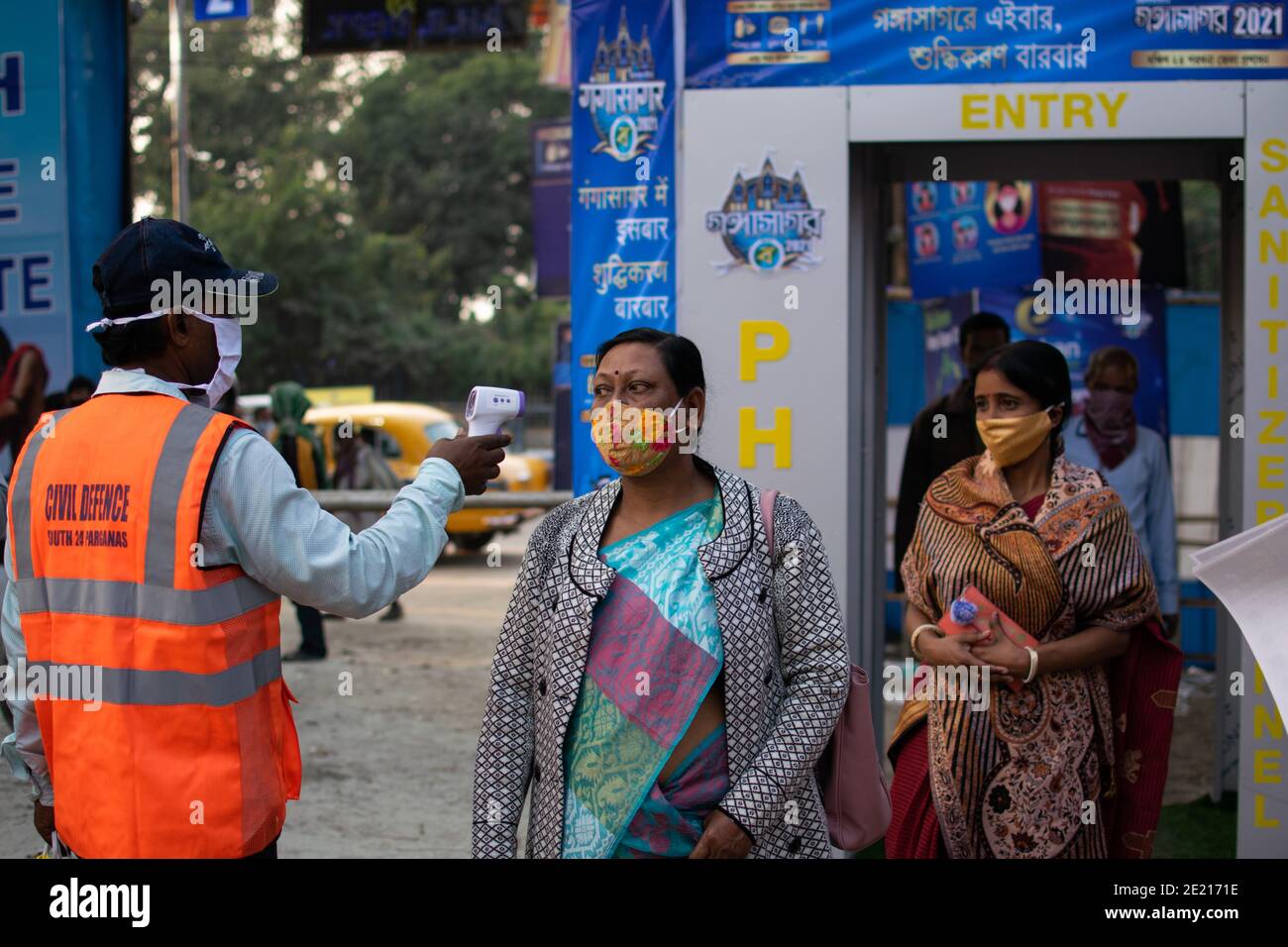 January 10, 2021, Kolkata, West Bengal, India: Civil defence workers are testing body temperate of everyone entering into the fairground. Gangasagar fair is a holy annual congregation of Hindu pilgrims. This takes place at Sagar Island located at the confluence of river Ganga and the Bay of Bengal. On the day of 'Makar Sankranti' (14th January) pilgrims take a holy dip at that confluence. Because of the ongoing pandemic situation, the whole thing is restricted under strong COVID19 protocols. This year, the main goals of the government are regular health check-up, sanitizing the place, avoiding Stock Photo