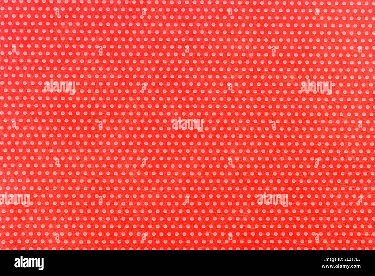 Textile homogeneous background color red in white fine polka dots, horizontal pattern. View from above. Emotionally funny. Stock Photo