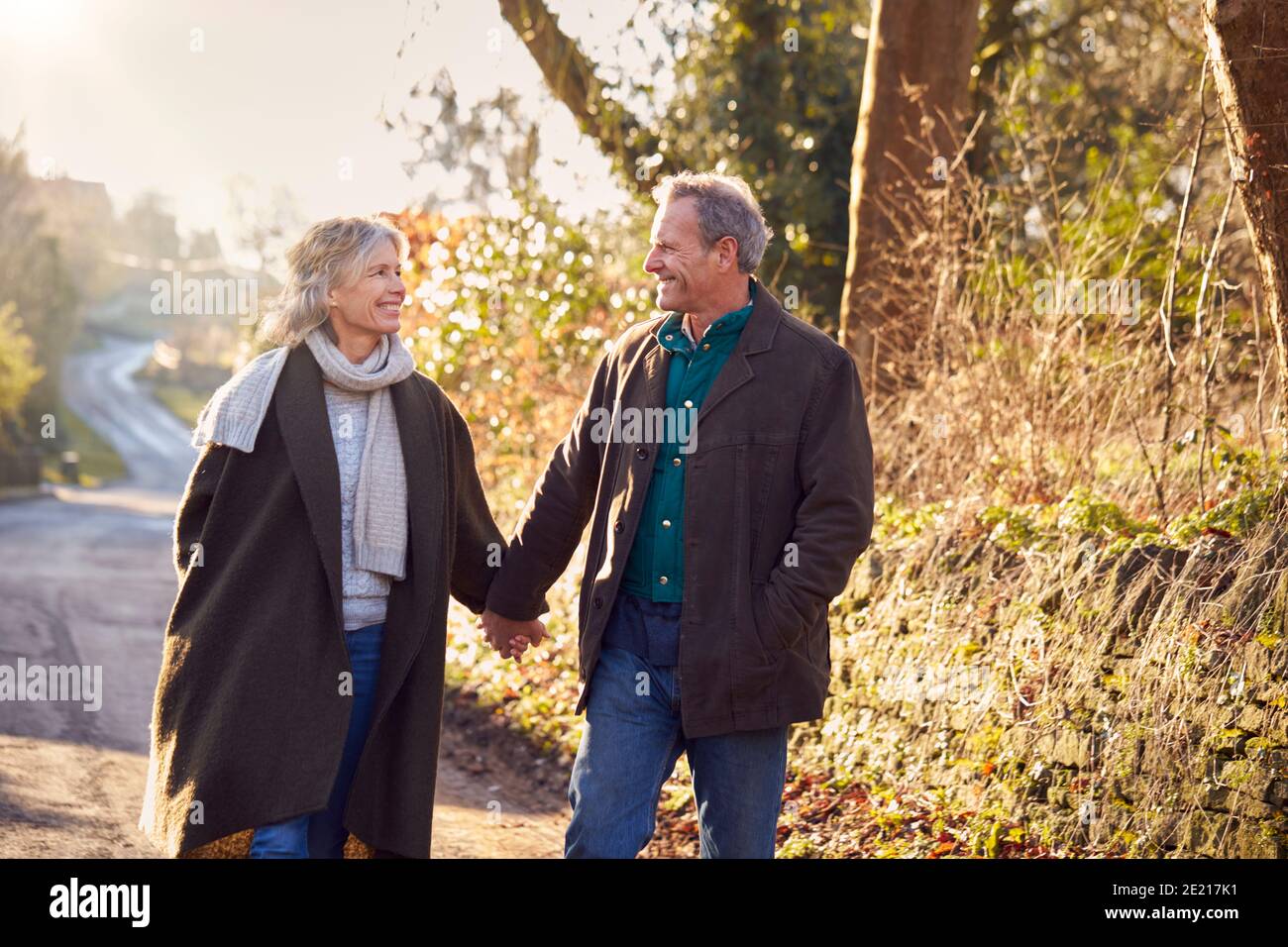 Retired Senior Couple Enjoying Winter Walk Through Village In Countryside Together Stock Photo