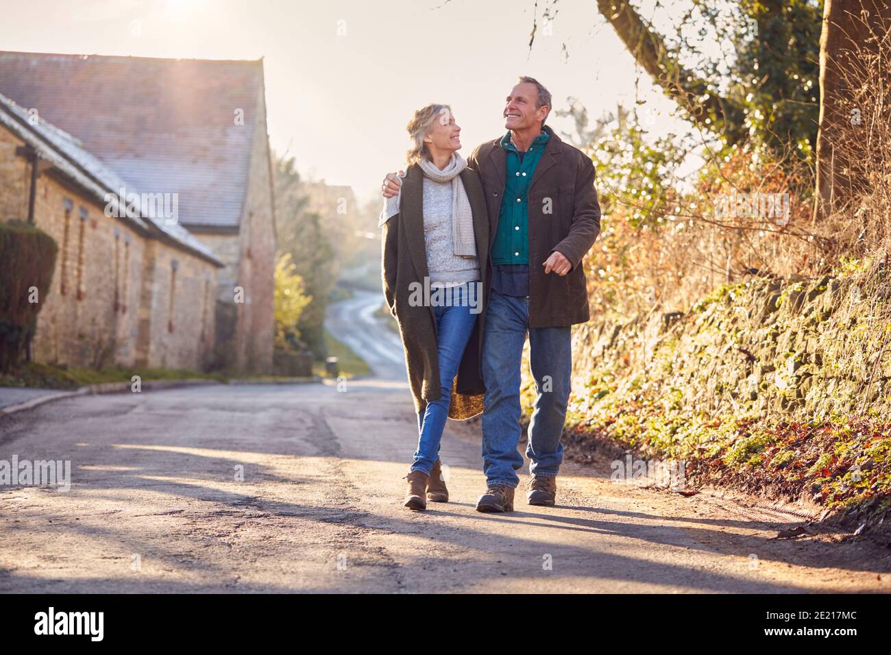 Retired Senior Couple Enjoying Winter Walk Through Village In Countryside Together Stock Photo