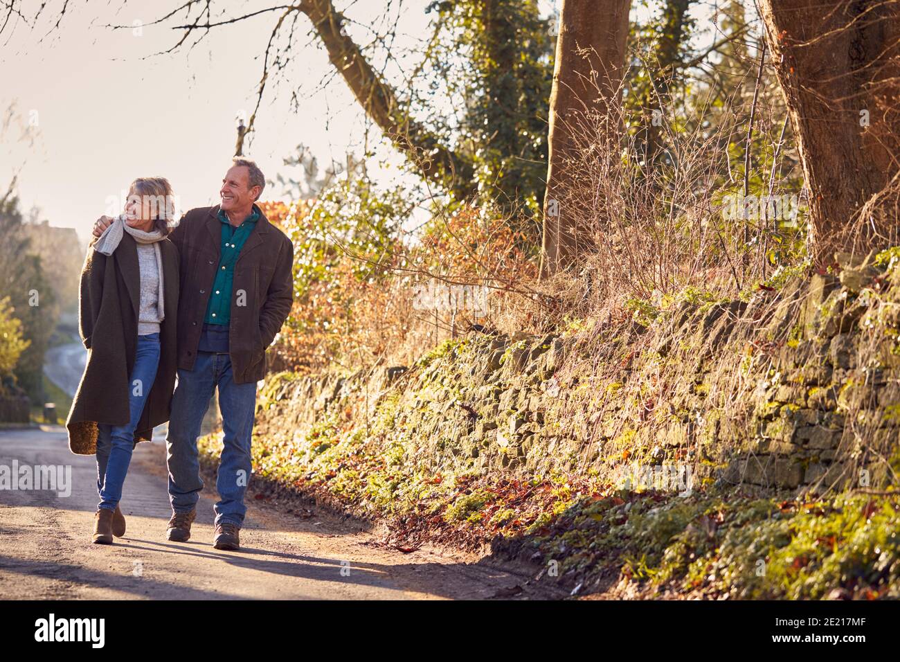 Retired Senior Couple Enjoying Winter Walk Through Village In Countryside Together Stock Photo