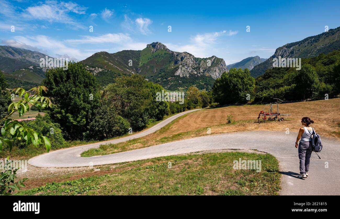 Woman hiking along quiet, winding road in mountains near Arenas De ...