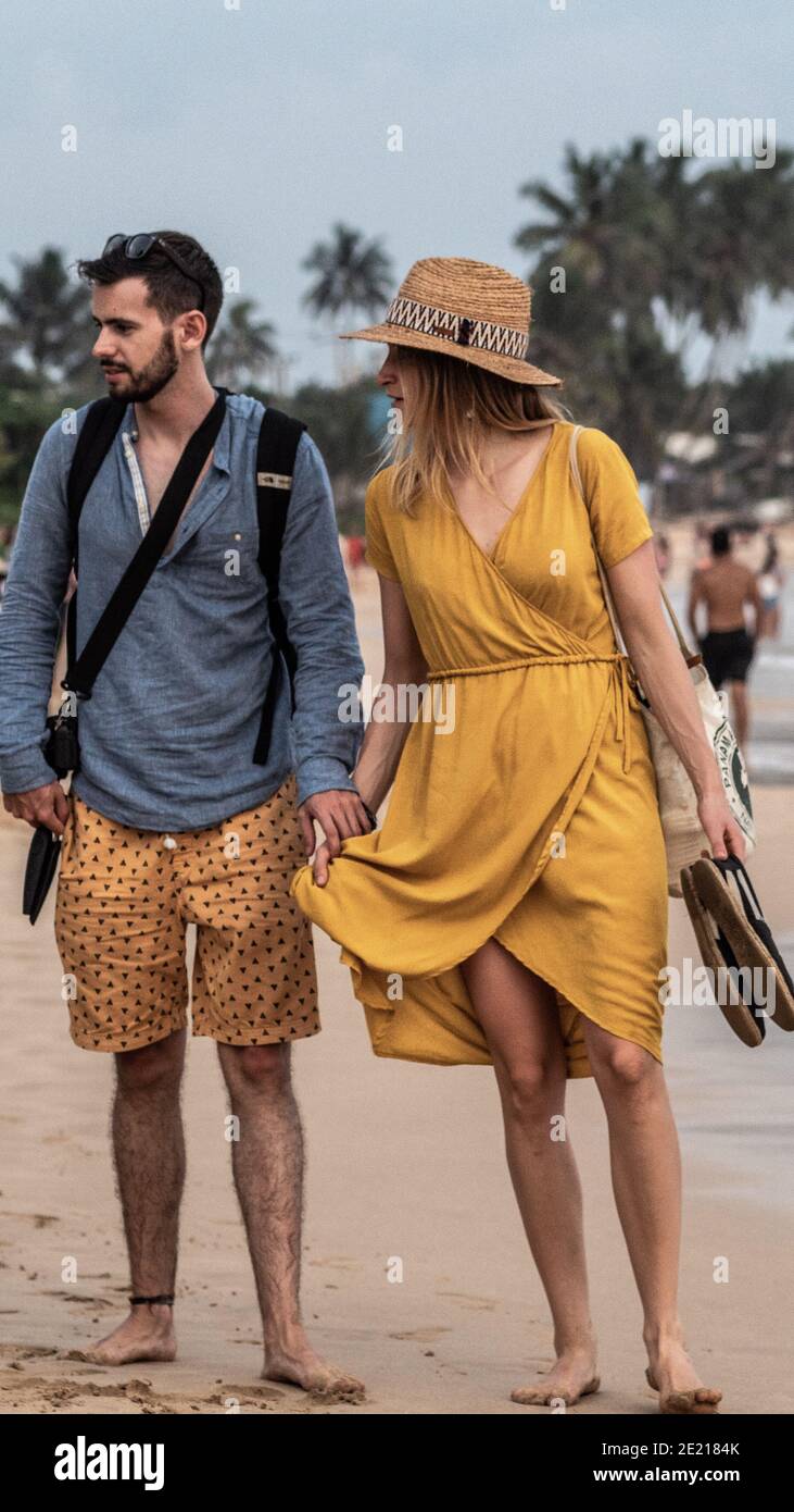 MIRRISA, SRI LANKA - March 17, 2019: Young caucasian couple in casual dress walking on the beach. Stock Photo