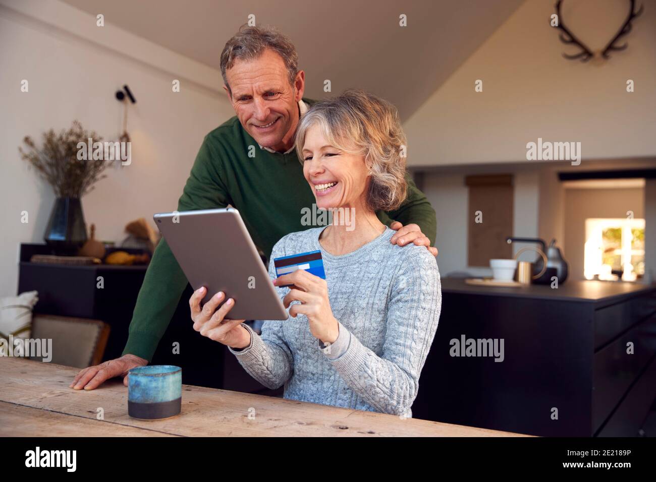 Retired Senior Couple At Home Buying Products Or Services Online With Digital Tablet And Credit Card Stock Photo