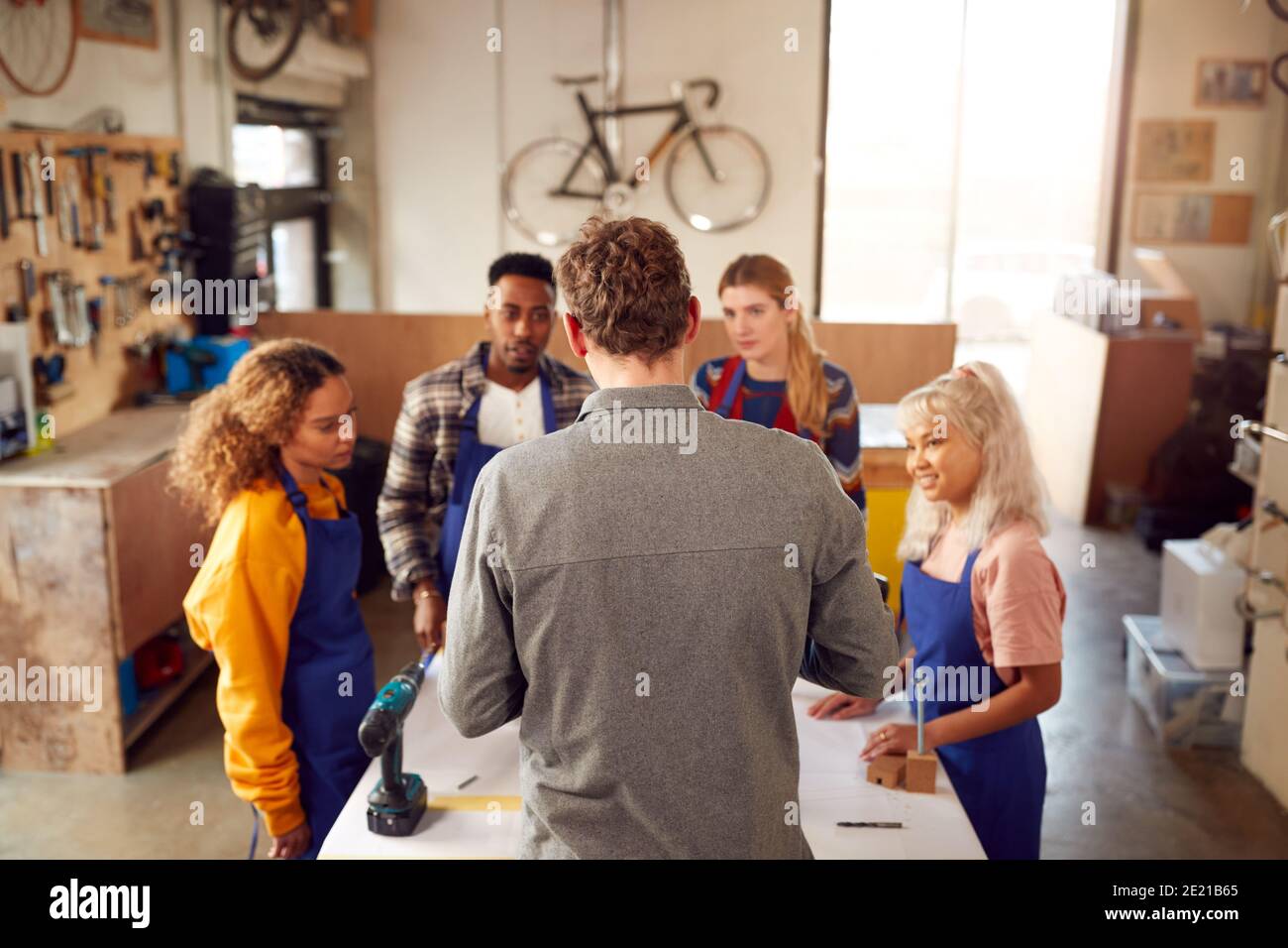 Multi-Cultural Team In Workshop Assembling Hand Built Sustainable Bamboo Bicycle Frame Stock Photo