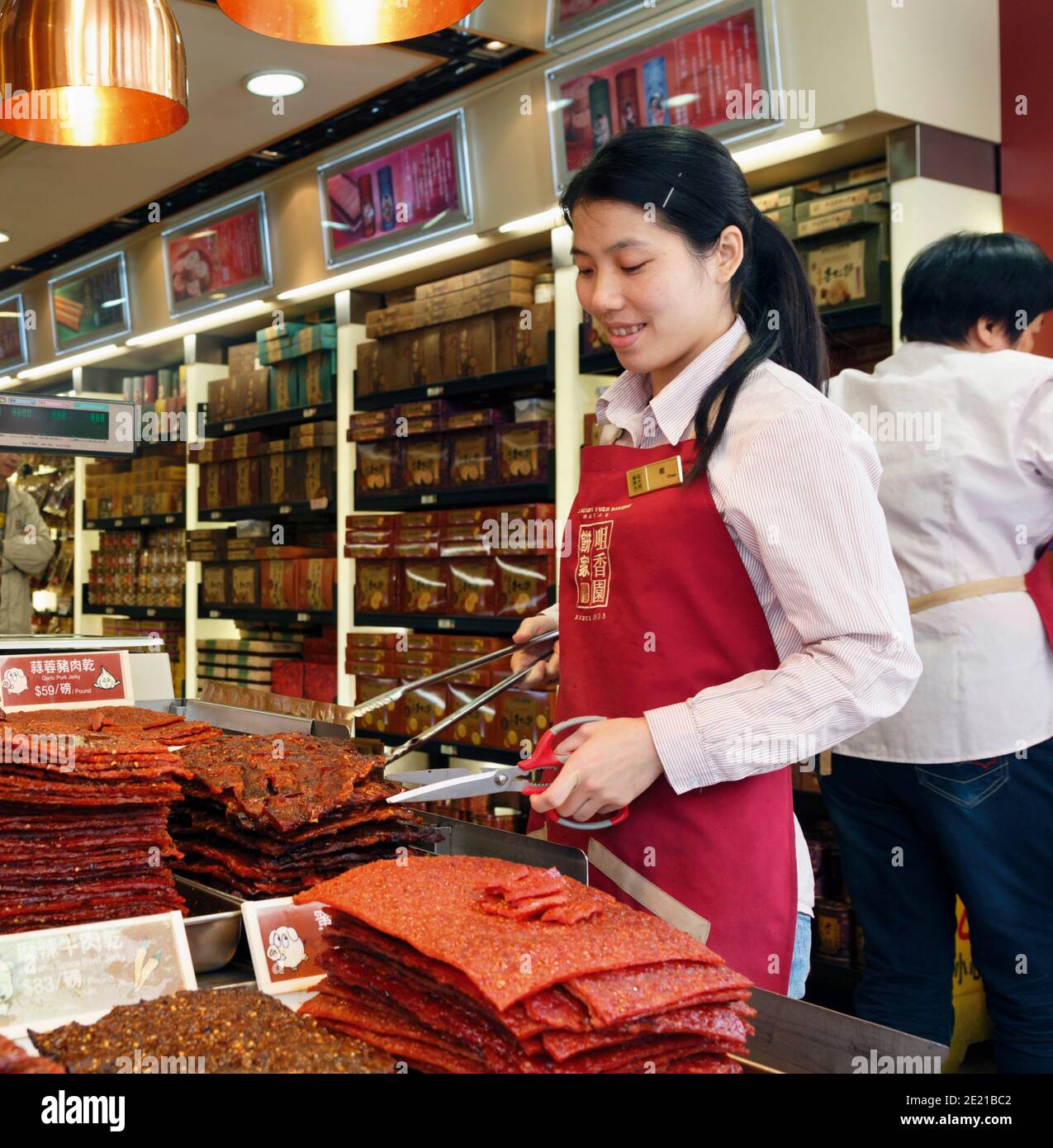 Young woman in the Choi Heong Yuen Bakery selling slabs of garlic pork jerky in Macau, China. Stock Photo