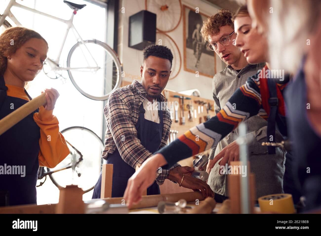 Multi-Cultural Team In Workshop Assembling Hand Built Sustainable Bamboo Bicycle Frame Stock Photo