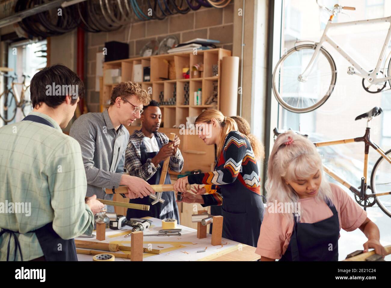 Multi-Cultural Team In Workshop Assembling Hand Built Sustainable Bamboo Bicycle Frame Stock Photo