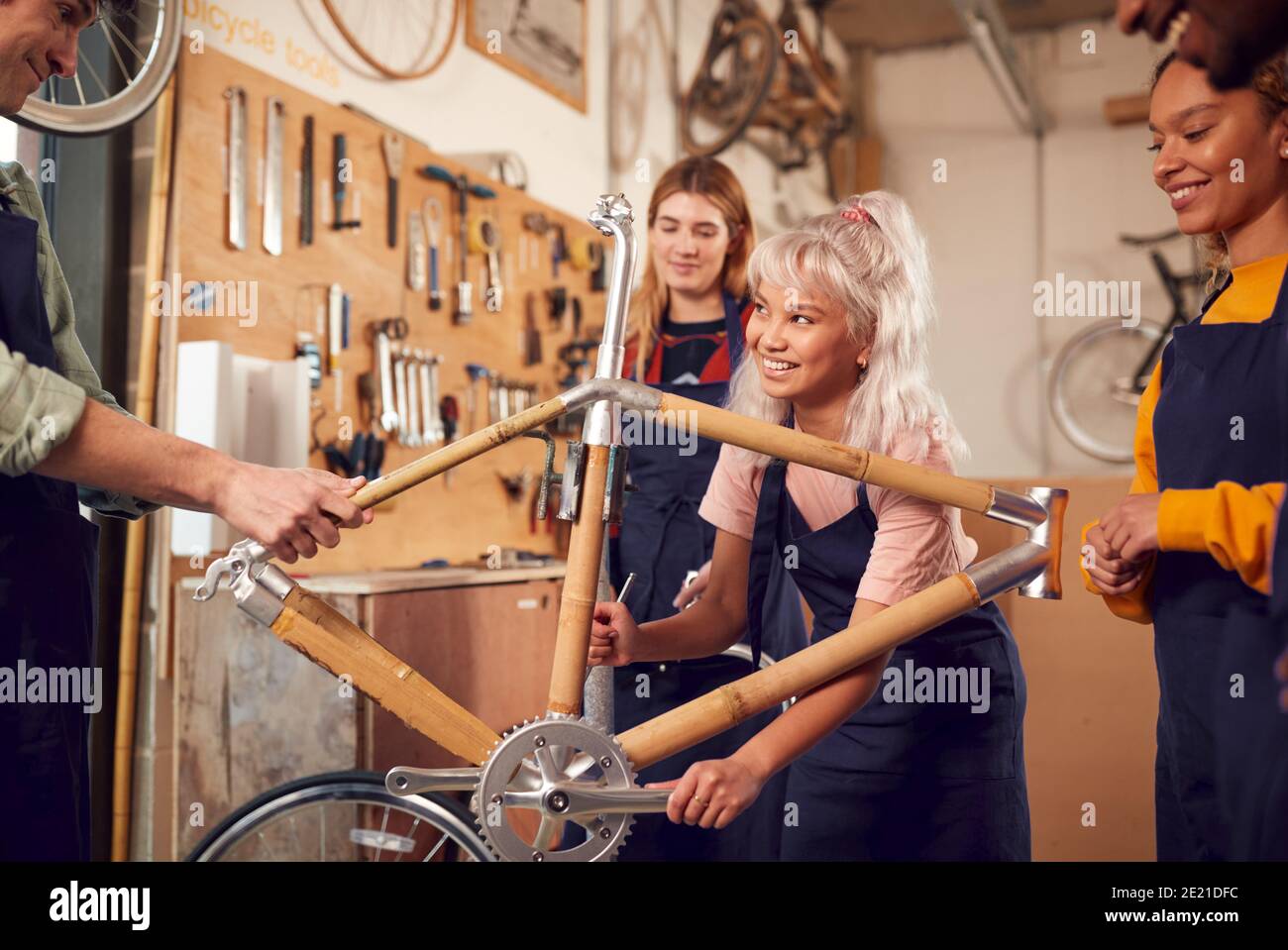 Multi-Cultural Team In Workshop Assembling Hand Built Sustainable Bamboo Bicycle Frame Stock Photo