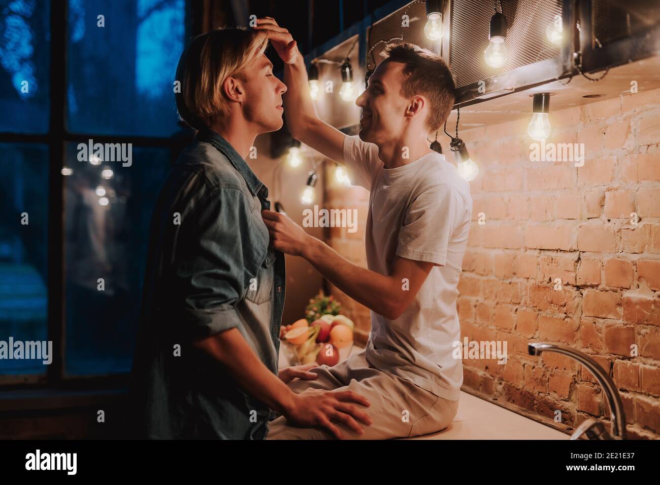 Loving gay couple at home. Two handsome men hugging and kissing on kitchen. LGBT concept. Stock Photo