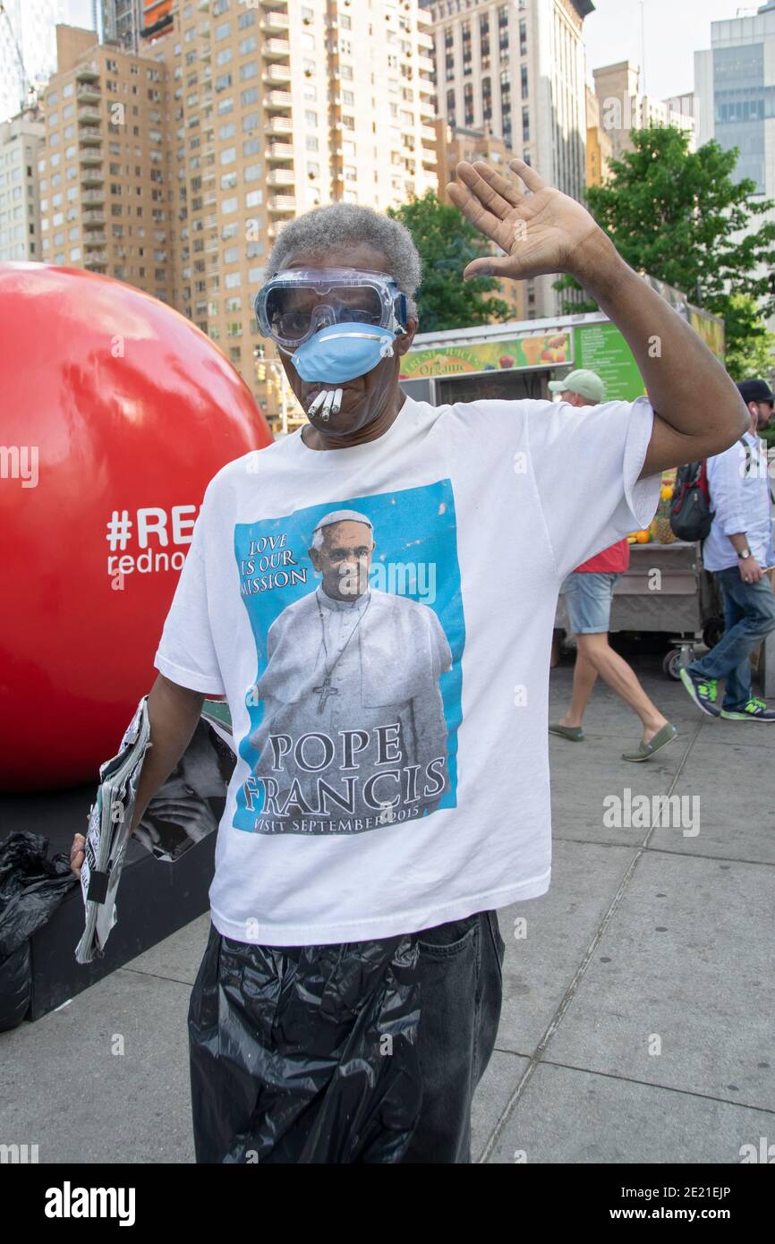A man wearing a Pope Francis shirt, goggles & mask and smoking 3 cigarettes.  Near Union Square Park in New York City Stock Photo