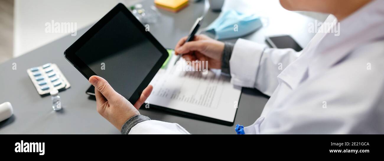 Unrecognizable female doctor using tablet while working Stock Photo