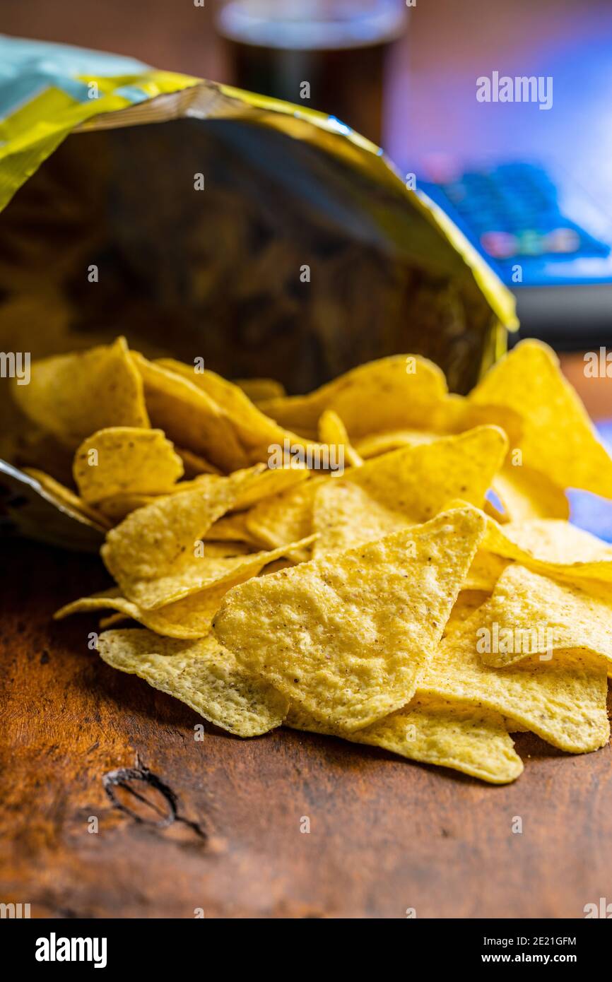 Salted tortilla chips. Yellow nachos triangle on wooden table. Stock Photo
