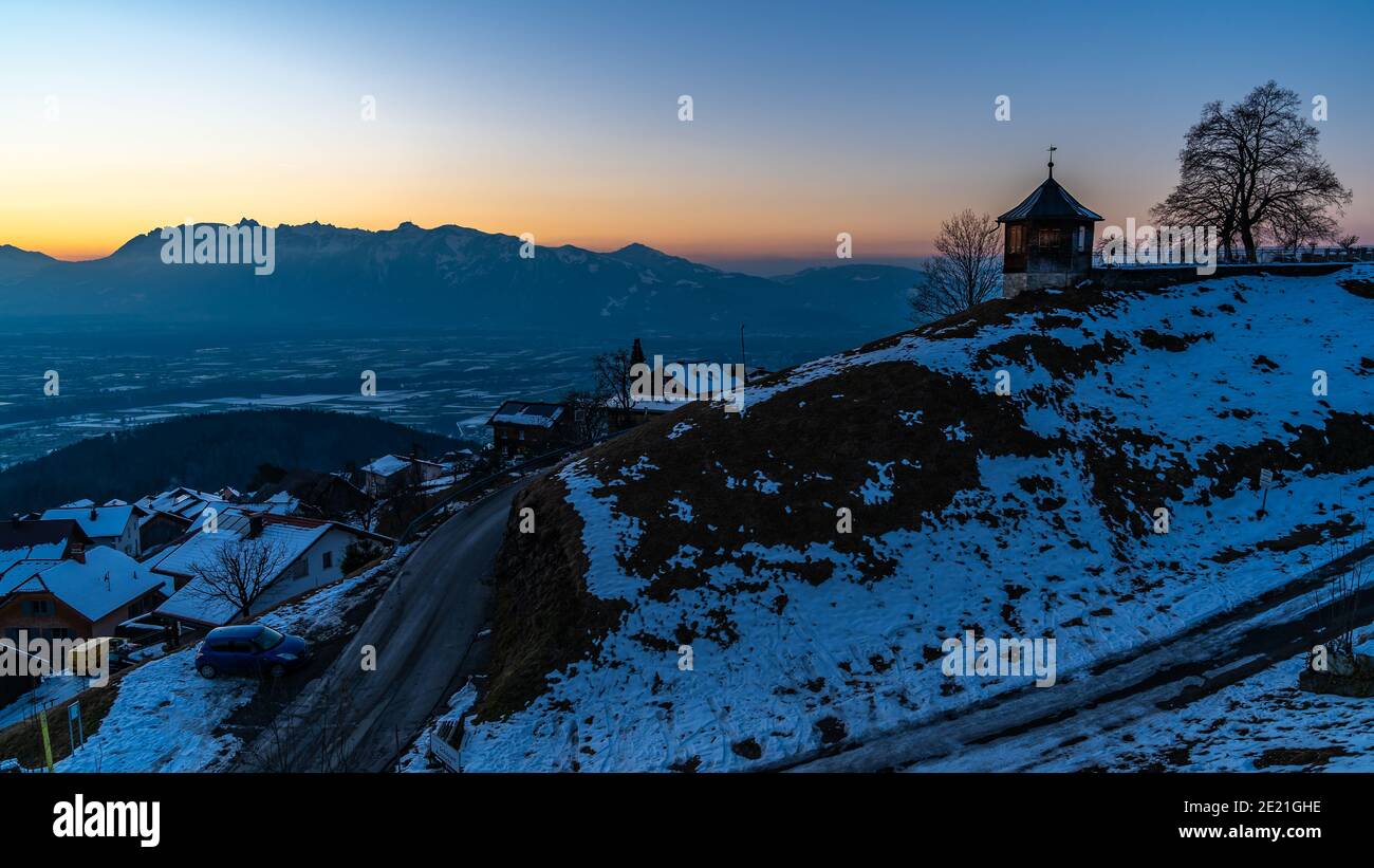 sunset, forest, house in the Austrian mountains. mountain range from Säntis under the afterglow. view to the Rhein valley from Viktorsberg, Vorarlberg Stock Photo