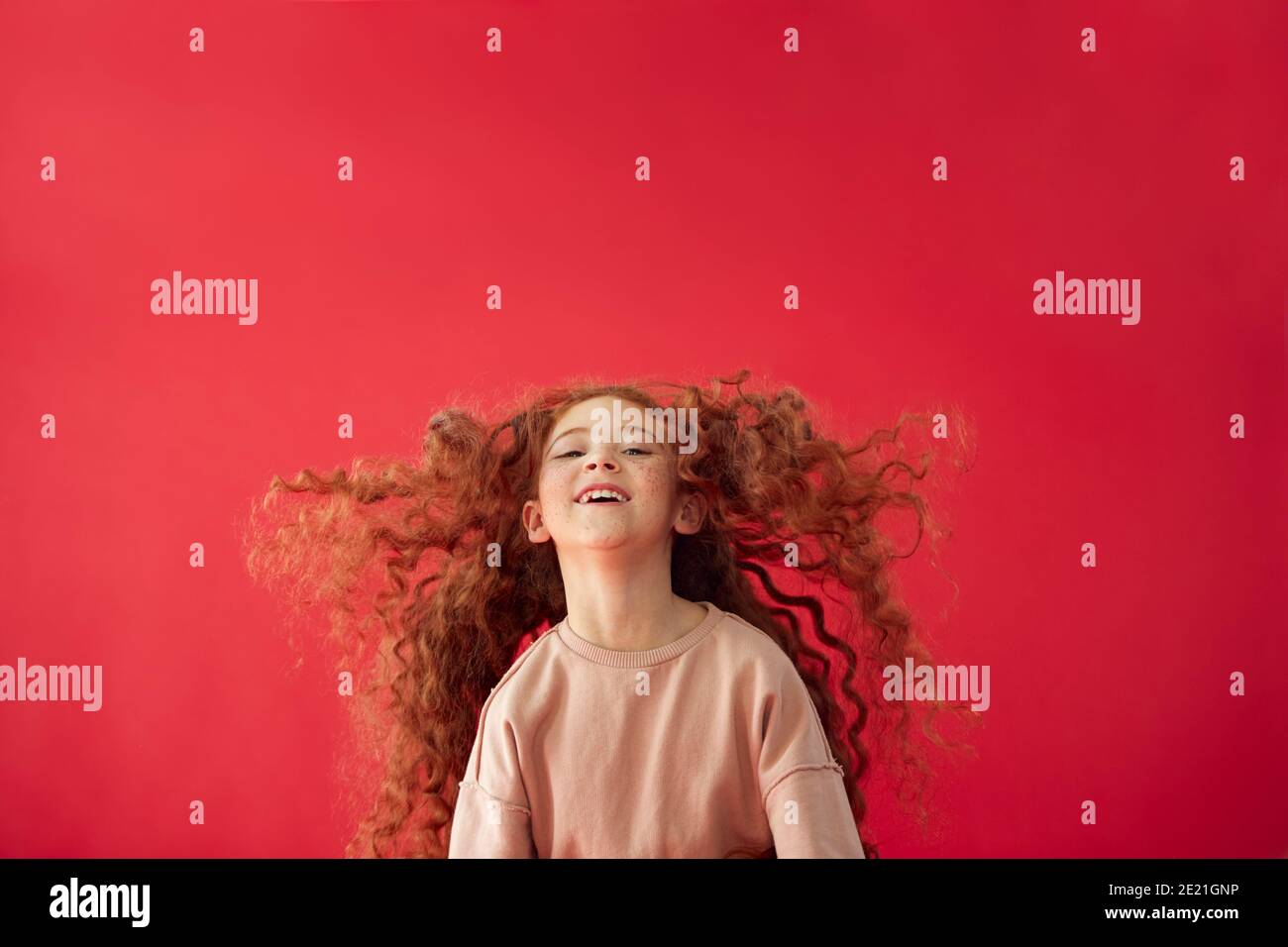 Portrait Of Girl With Long Red Hair Jumping In Air Against Red Studio ...