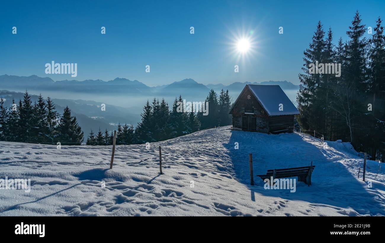 Landscape over Viktorsberg in the Austrian mountains. Alpine hut at the edge of the forest on the snowy field. the snow glitters, glows on the meadow Stock Photo