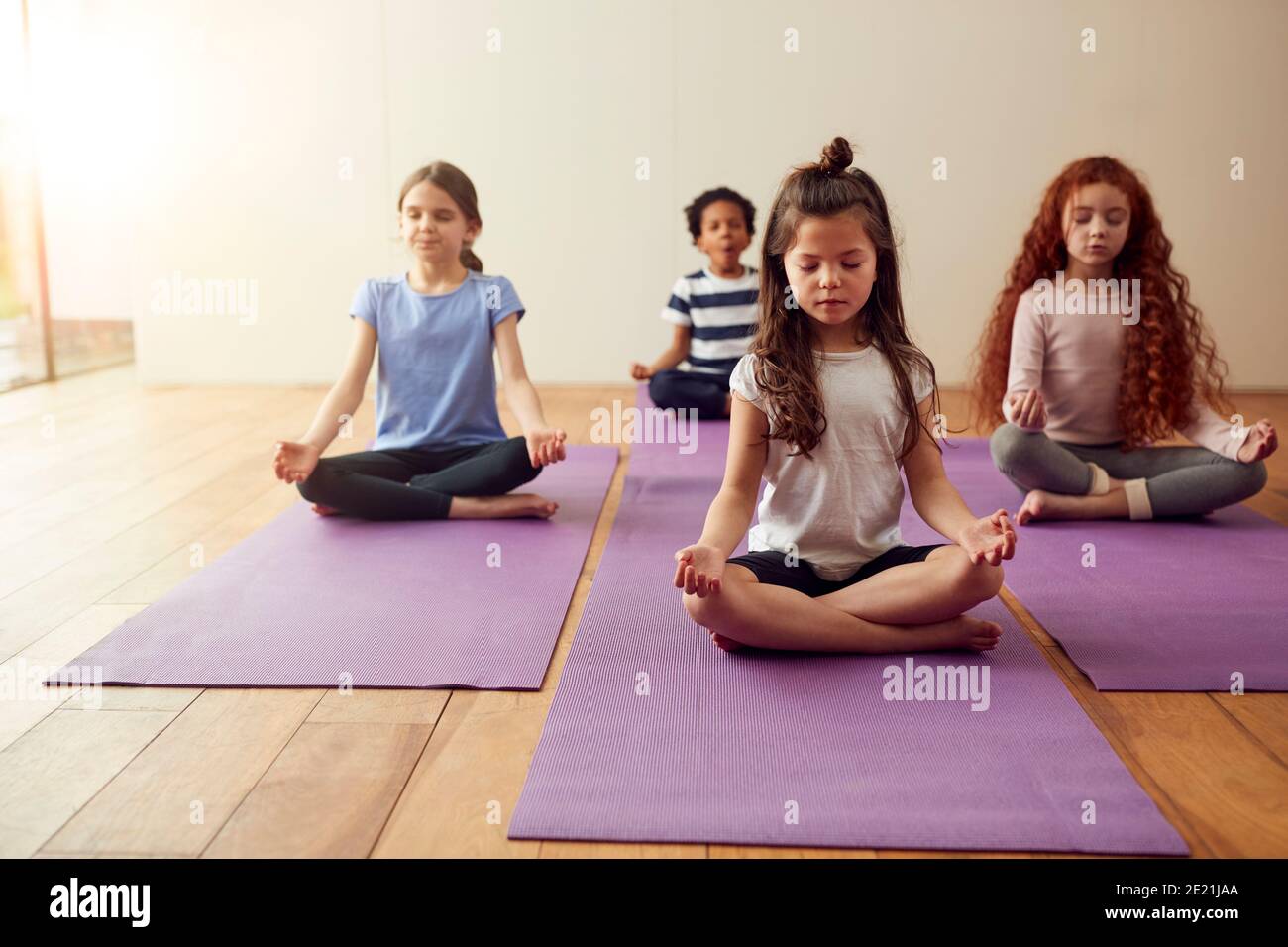 Group Of Children Sitting On Exercise Mats And Meditating In Yoga ...