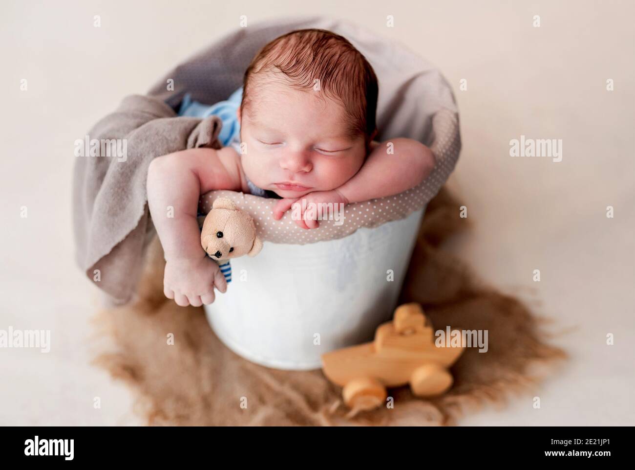 Newborn sleeping in cradle holding toy and lying head on hand Stock