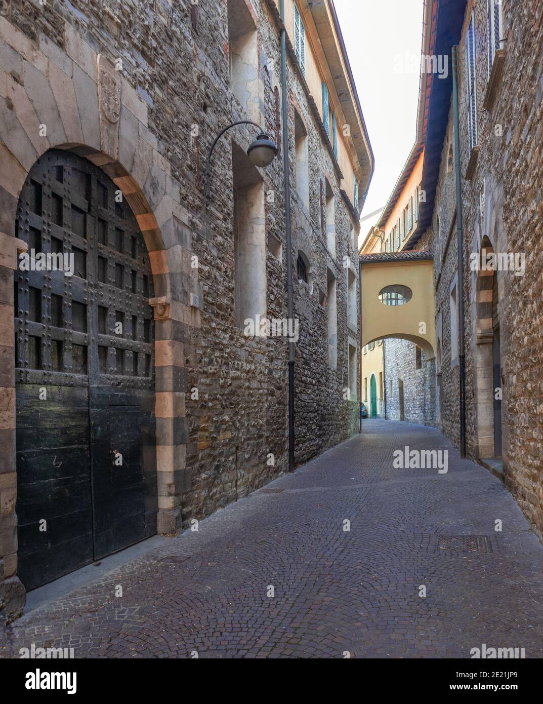 view along a medieval, dark and narrow alley with ancient stone houses.Como, Lombardy.Italy Stock Photo