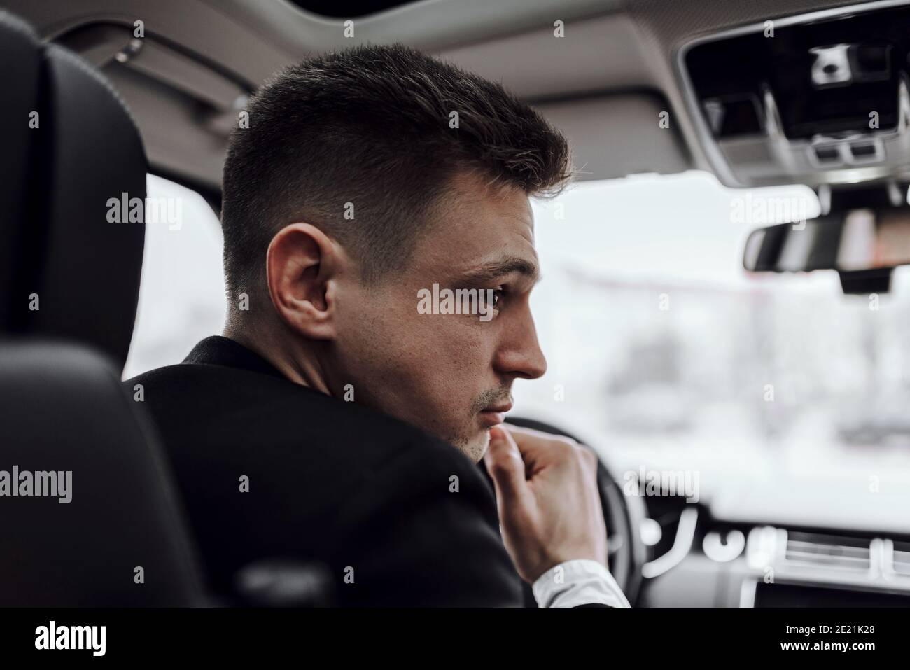 Close up of young man driving in car while renting it. Rent and trade-in concept Stock Photo