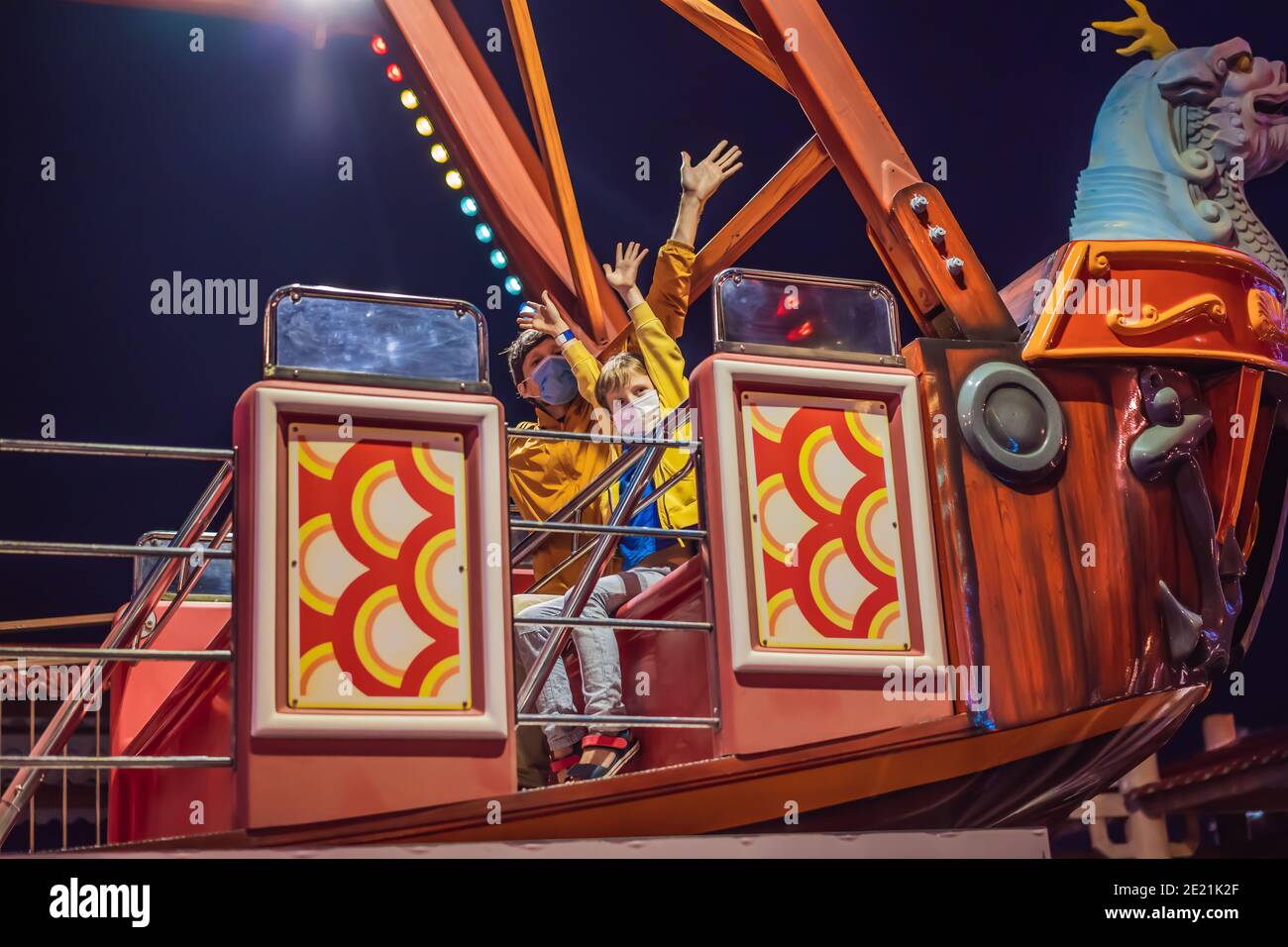 Father And Son Riding A Carousel Wearing A Medical Mask During Covid 19