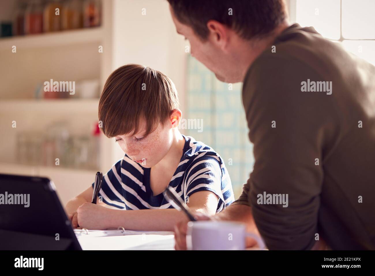 Father Helping Son With Homework Sitting At Kitchen Counter Using ...