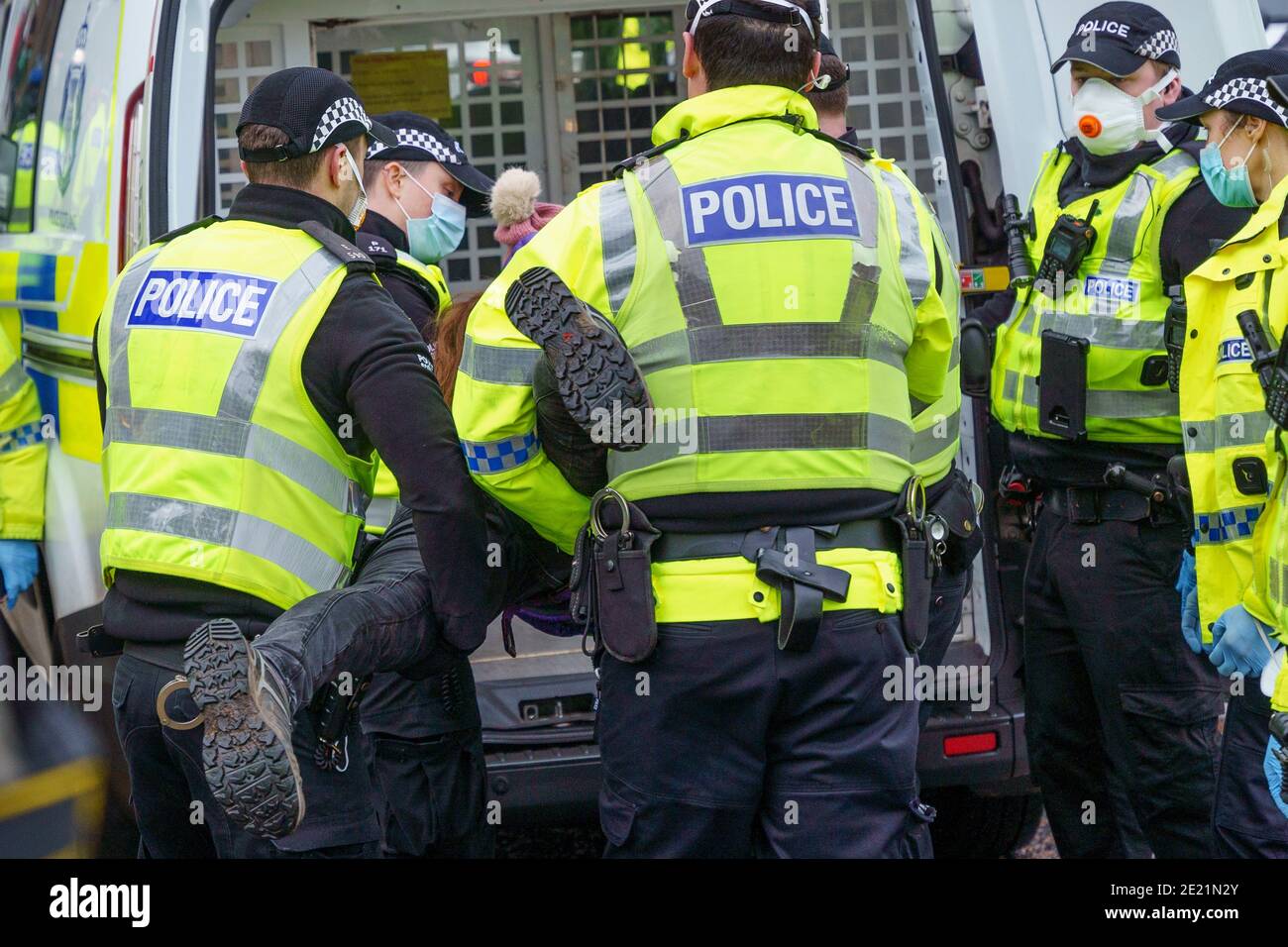Edinburgh, Scotland, UK. 11 January 2021. Protester arrested in violent scenes at anti lockdown demonstration at Scottish Parliament in Edinburgh today. Several protesters took part but  a heavy and aggressive police presence prevented demonstration and planned march to Bute House. During national Covid-19 lockdown such protests are illegal and police advised people not to attend the demonstration. Pic; Female protester is arrested and bundled into a police van.  Iain Masterton/Alamy Live News Stock Photo