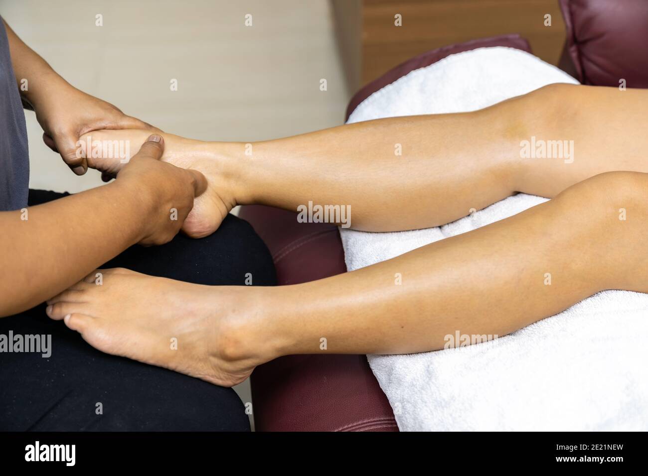 Close up asian woman do foot massage at home with face mask while city lockdown for social distance due to coronavirus pandemic. Massage is one of ser Stock Photo