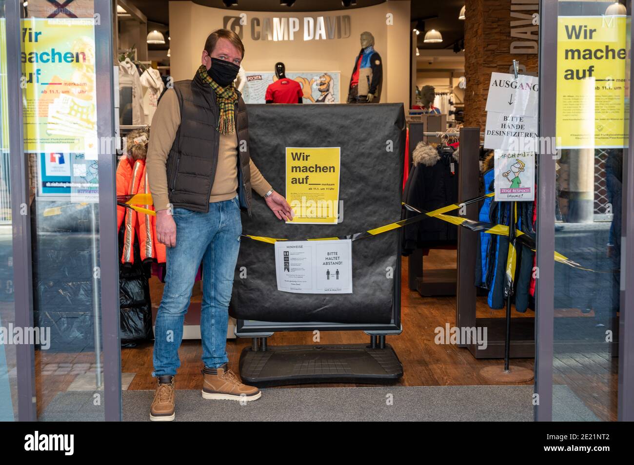Trier, Germany. 11th Jan, 2021. Patrick Sterzenbach from the City  Initiative Trier (CIT) stands at the open door of his shop in Trier's city  centre. He wants to draw attention to the