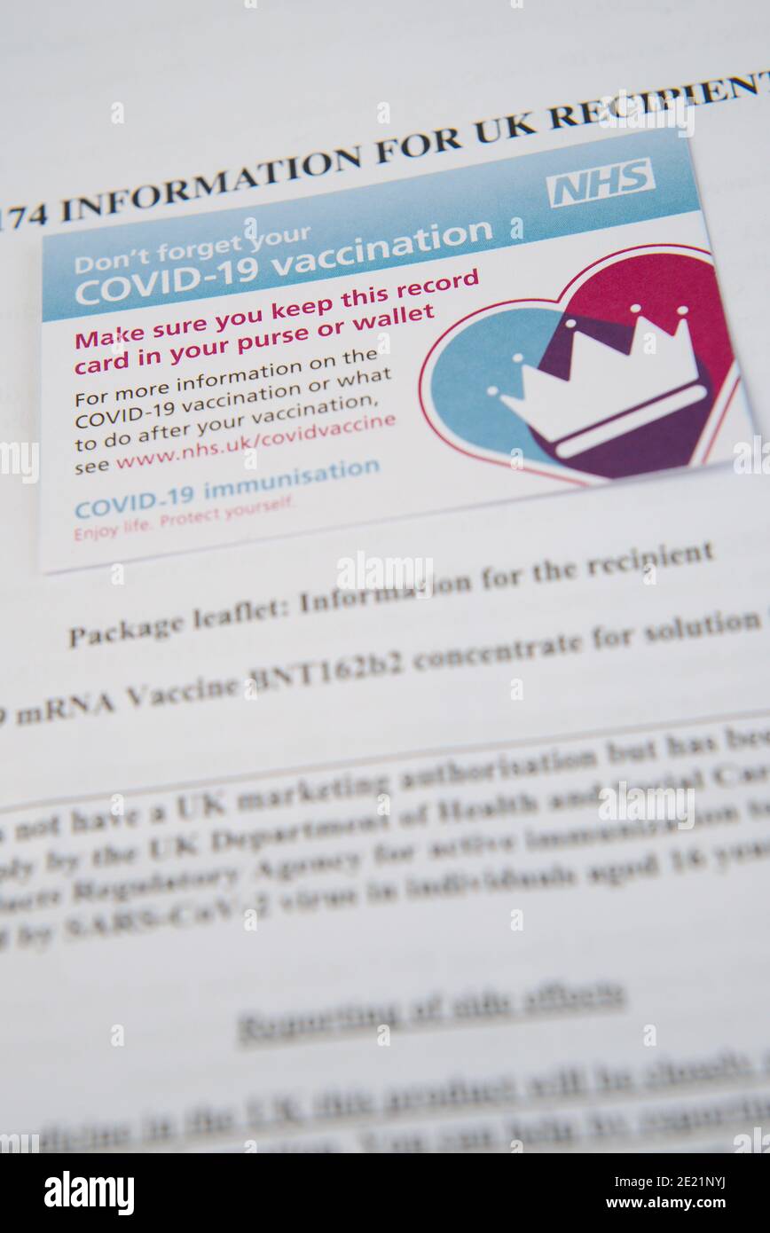 Covid 19 vaccination record card and information for recipients of one of the coronavirus vaccines being rolled out by the NHS in the UK. Stock Photo