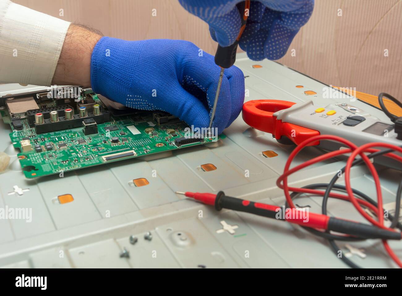 Repair of LCD TV in service center. Hands of engineer remove monitor parts with screwdriver and test it with multimeter. Selective focus. Stock Photo