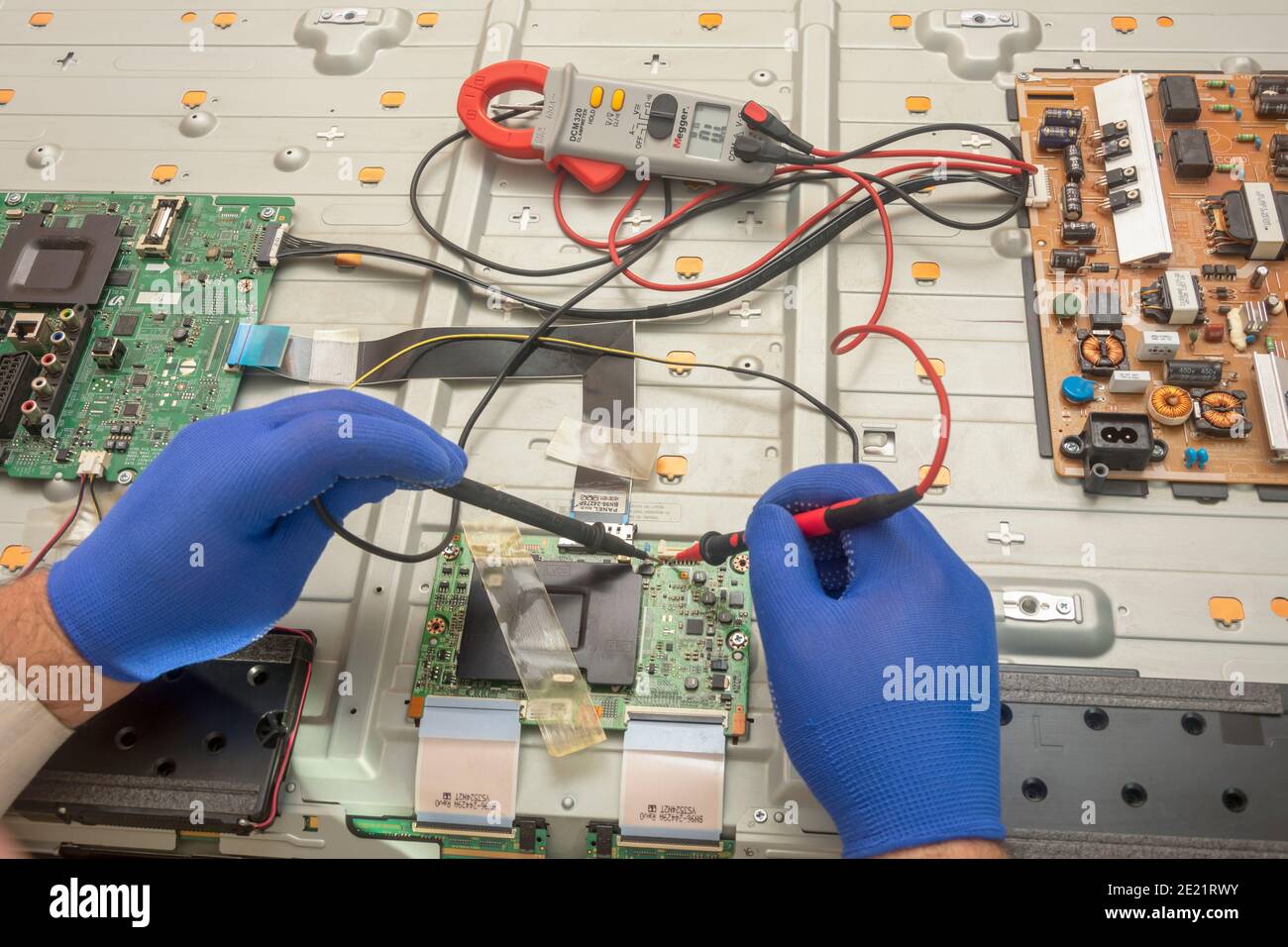 Electronic engineer repairs large TV in service center. Gloved hands