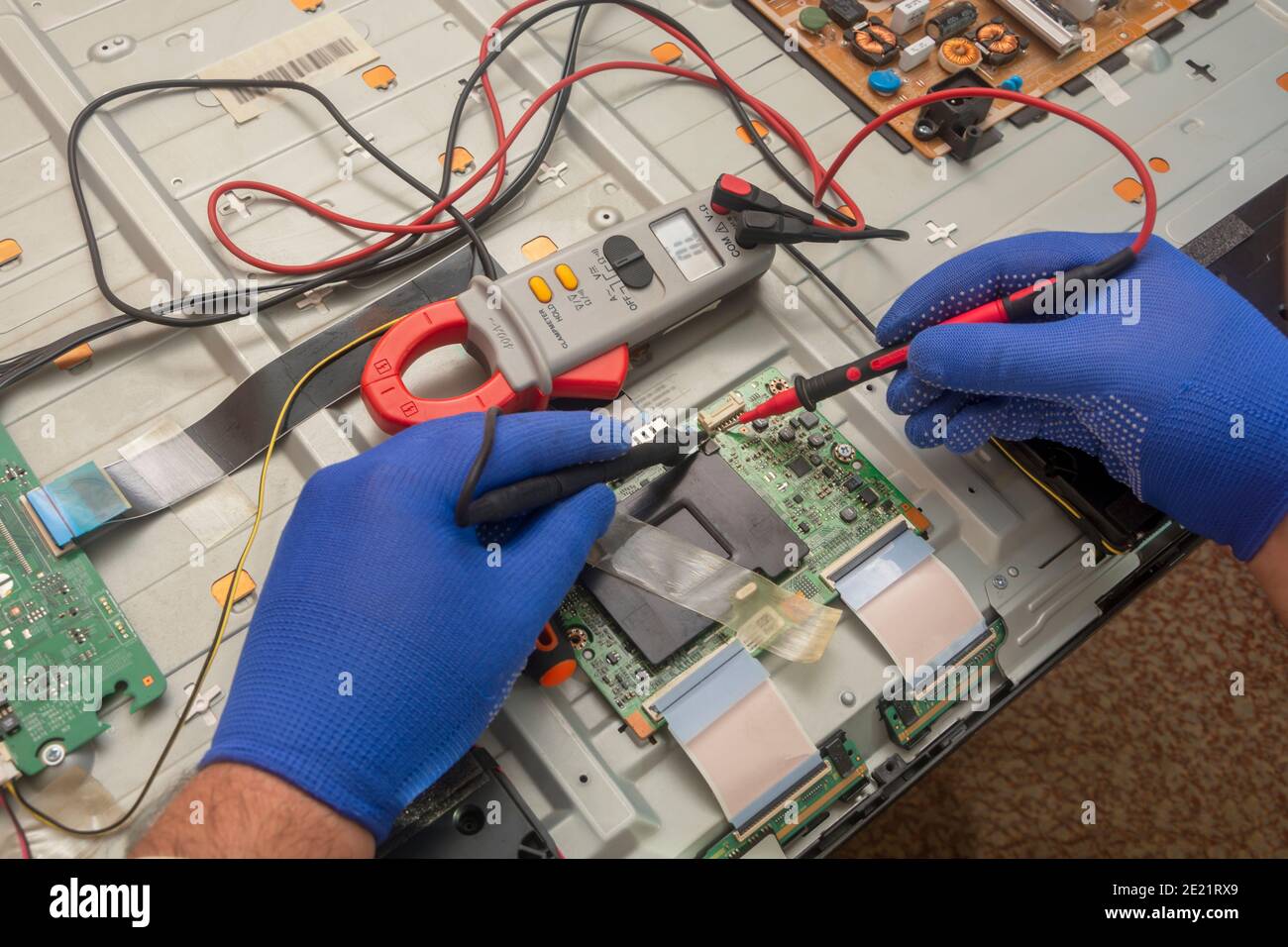Repair of LCD TV in service center. Diagnostics of printed circuit board with multimeter probe. Selective focus. Stock Photo